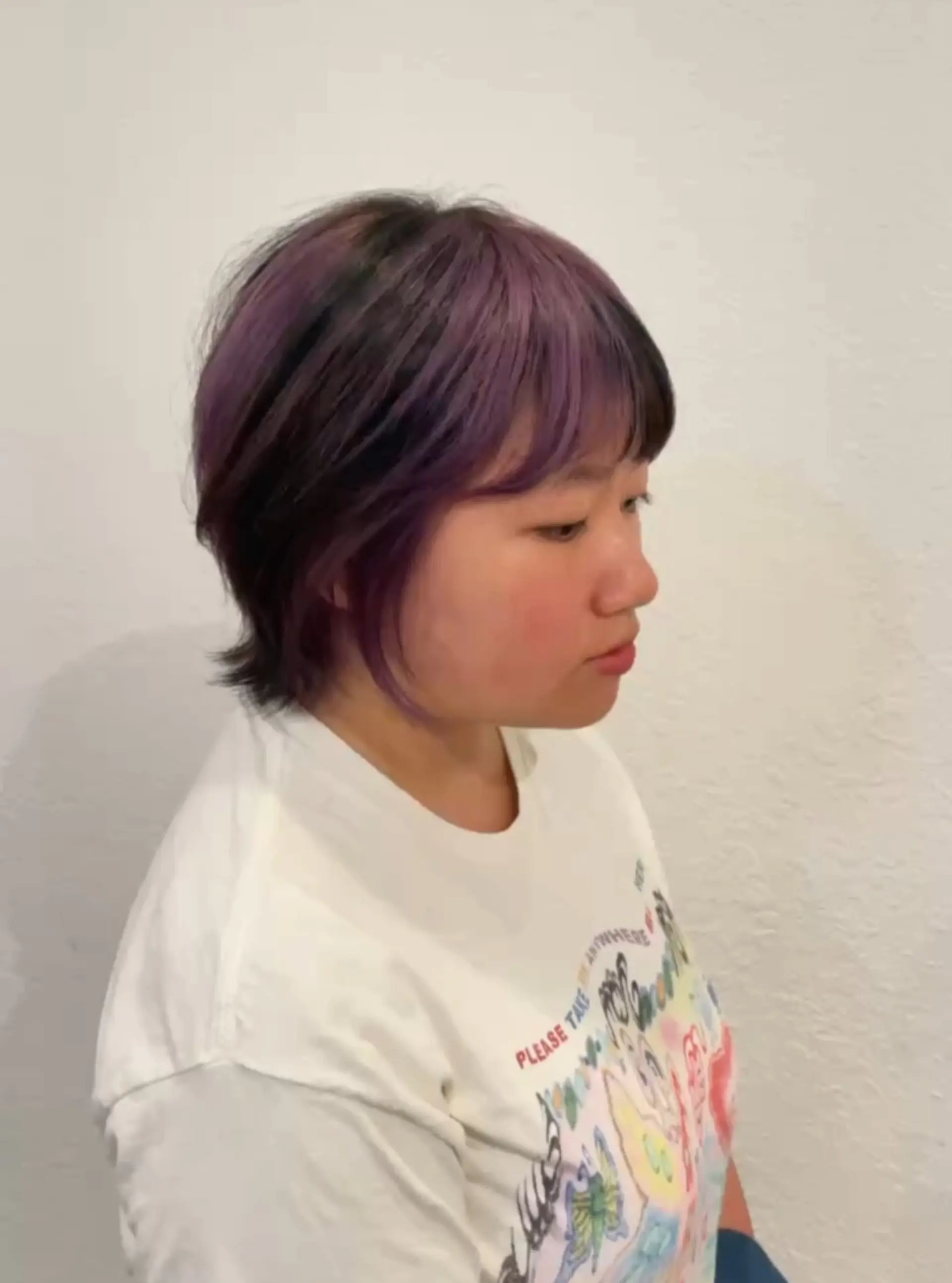 A short, layered wolf cut with full textured bangs and vibrant violet balayage highlights over a dark base. 1