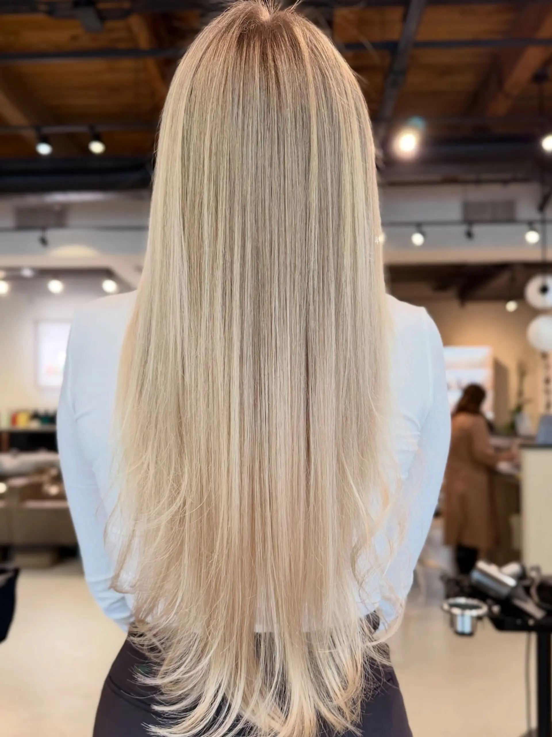 Long, straight bright blonde hair with seamless airtouch blending and a subtle root shadow. 1