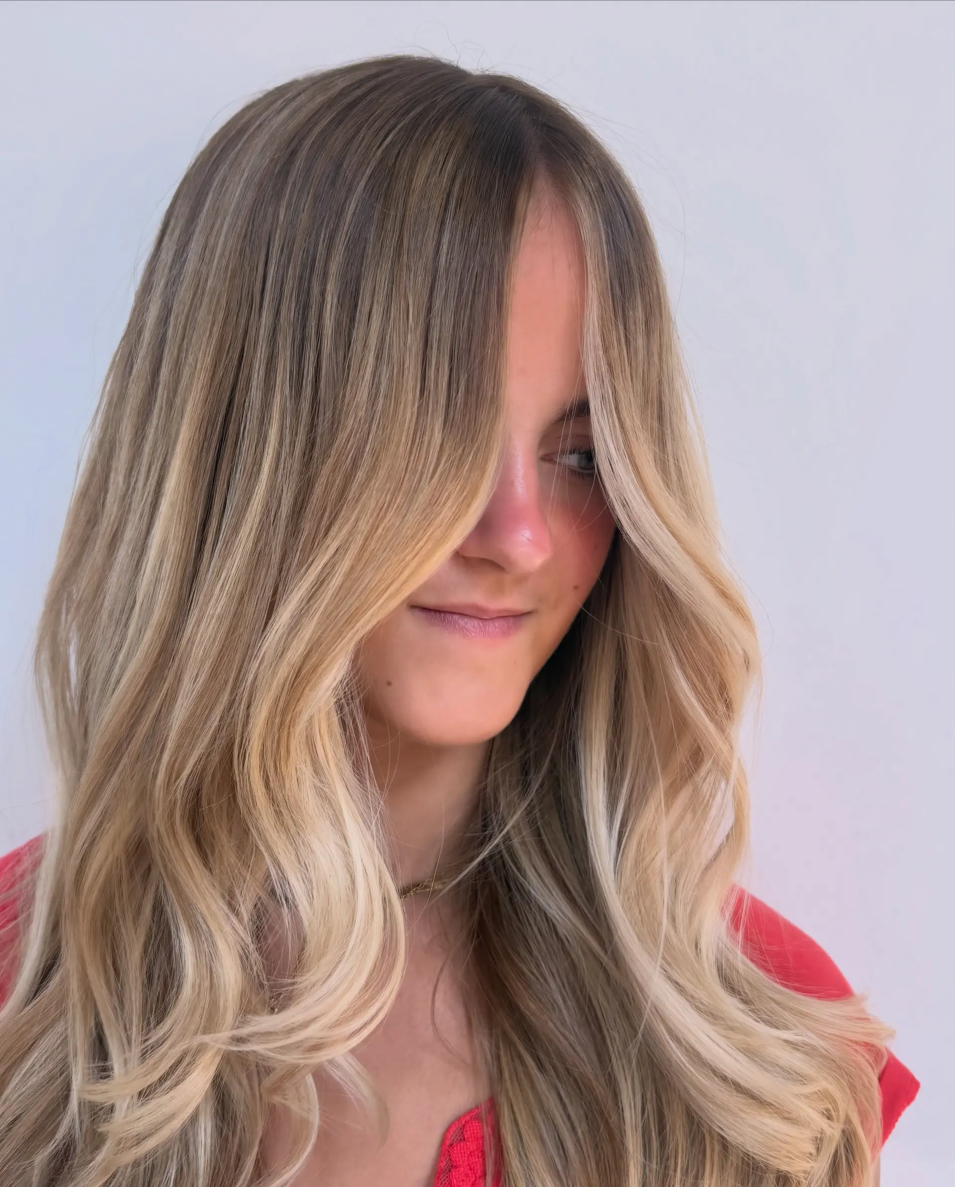 Long honey blonde balayage styled into soft, flowing waves with bright face-framing strands. 1