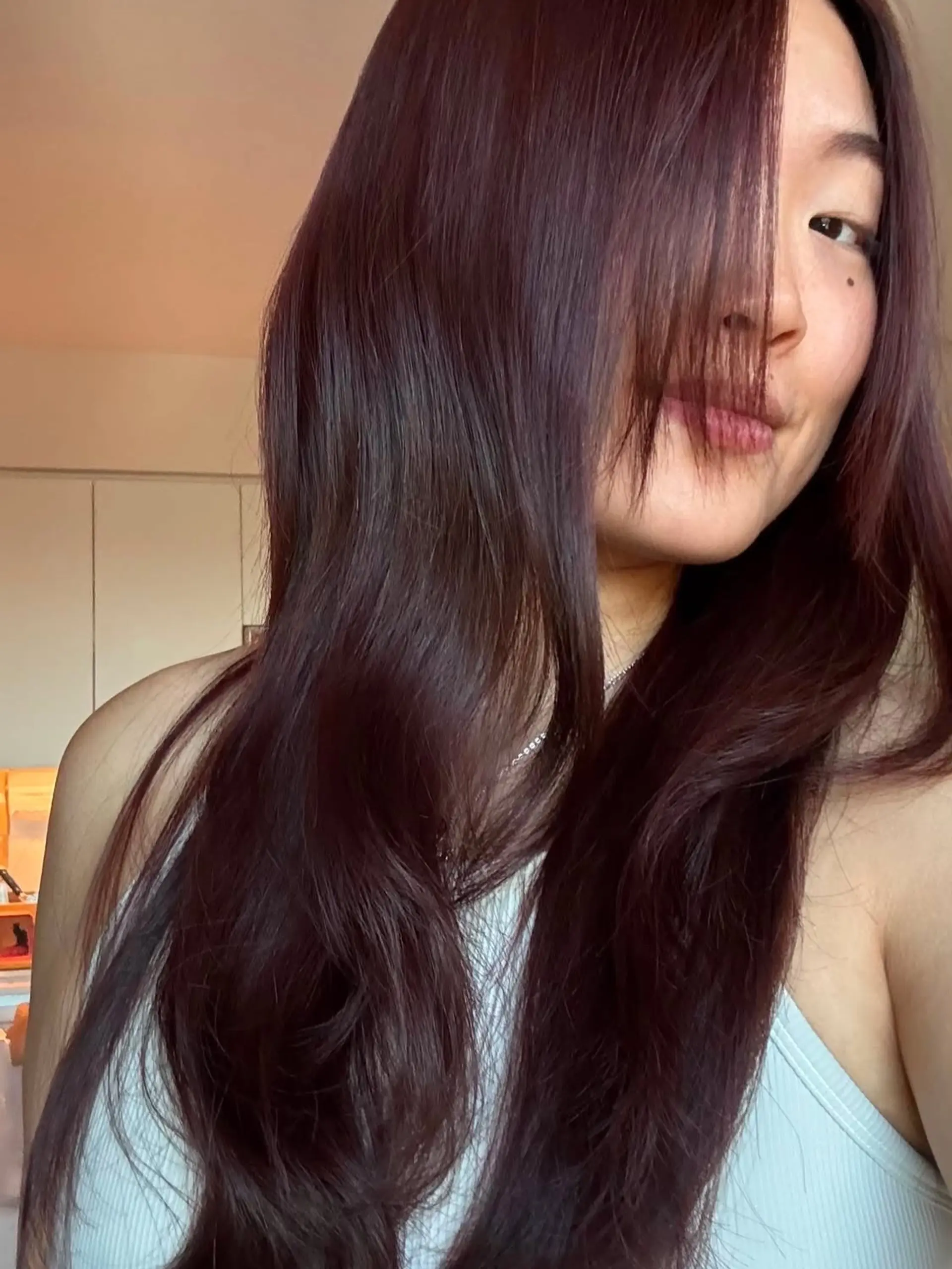 Long deep copper-red hair cut with soft cascading layers and face-framing bangs, styled in smooth, natural waves. 1