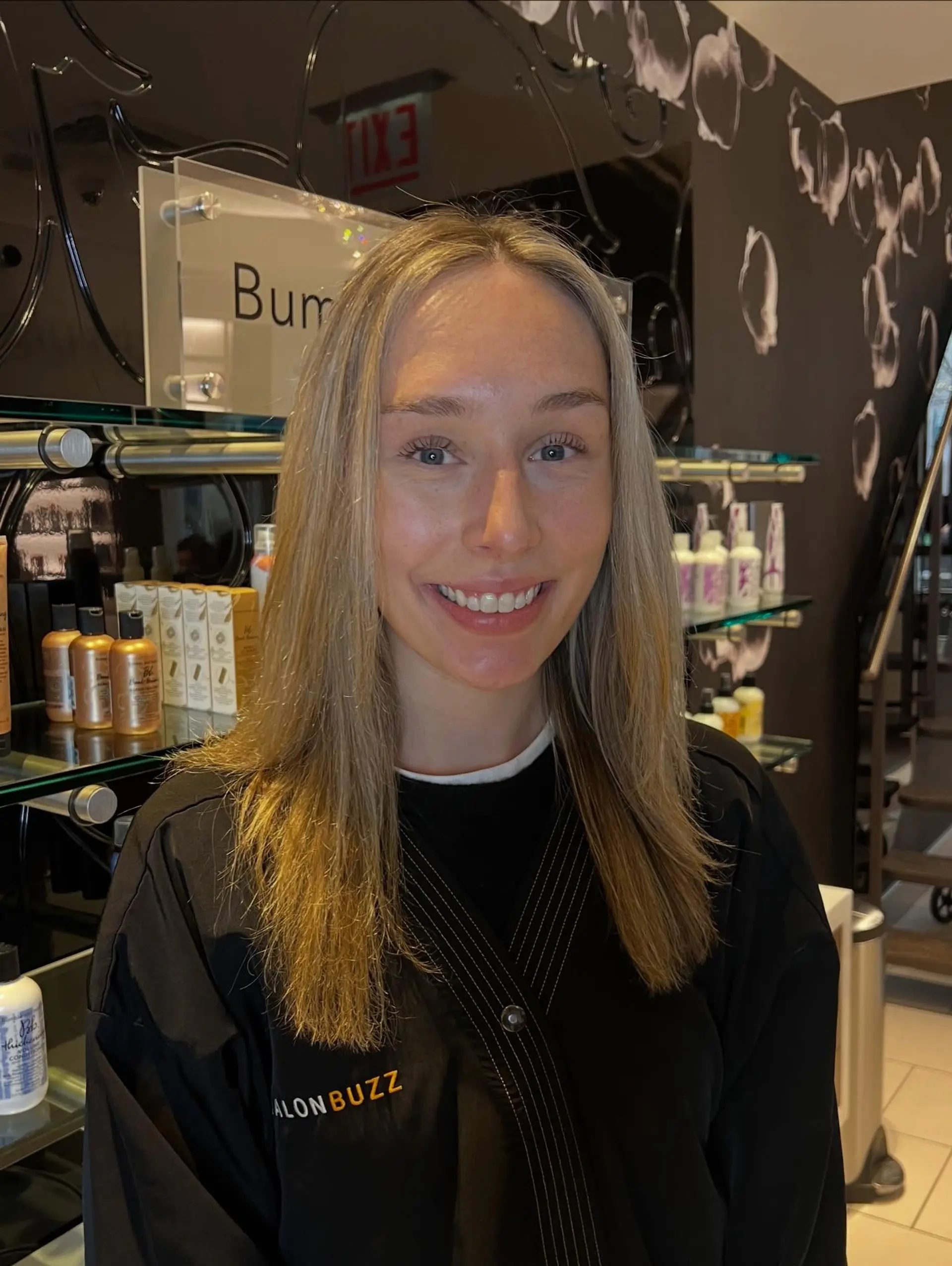 Medium-length straight hair styled with a center part and featuring a natural, soft blonde balayage. 1