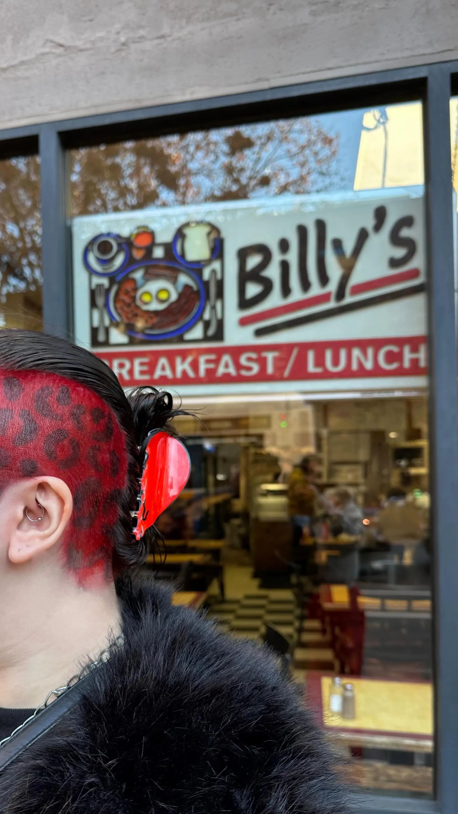 A bold undercut buzz dyed vibrant red with black leopard print pattern work, paired with slicked-back dark hair. 1