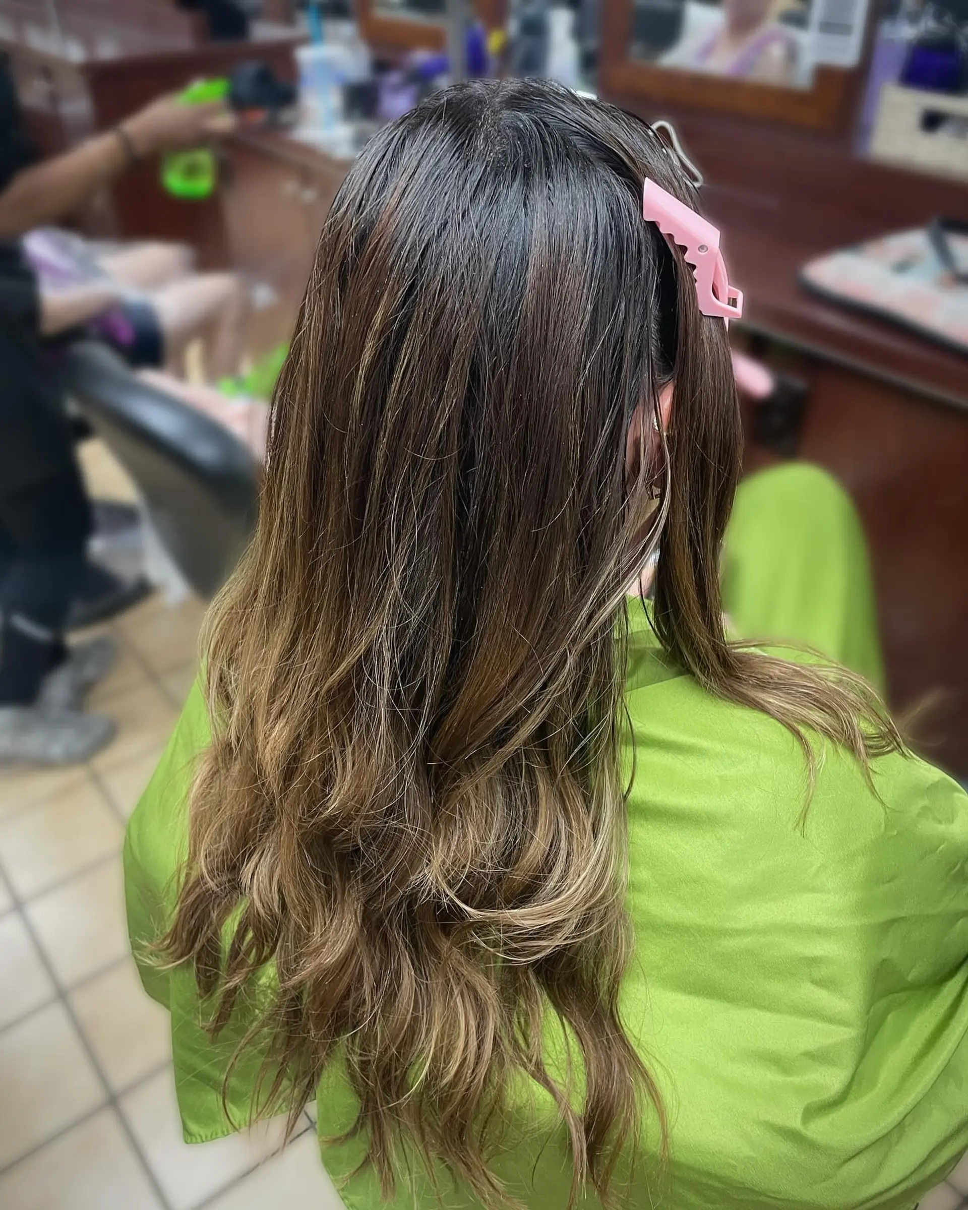 Long dimensional brunette hair styled in loose waves with fine honey and caramel highlights blended throughout. 1