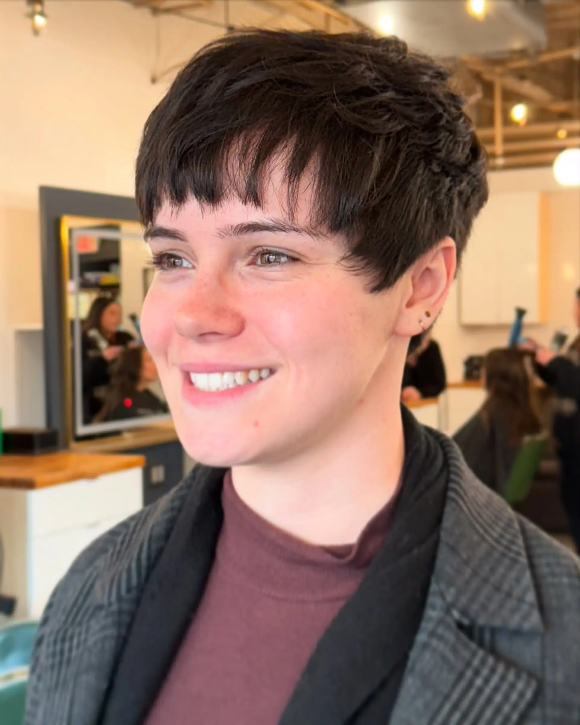 A short, piecey pixie cut styled forward with soft, textured micro bangs. 1