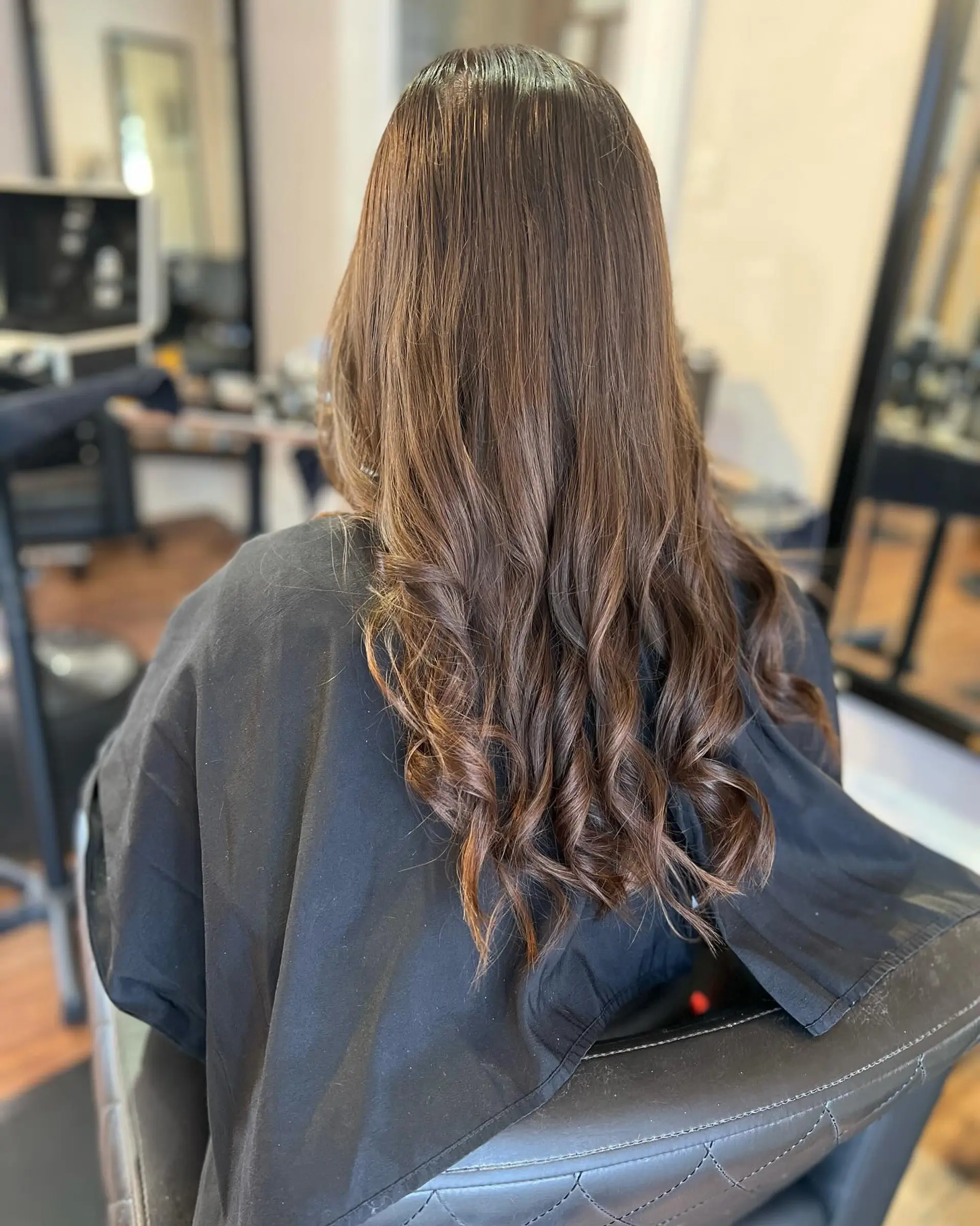 A long, rich brunette hairstyle featuring smooth mid-lengths and loose curling through the ends. 1