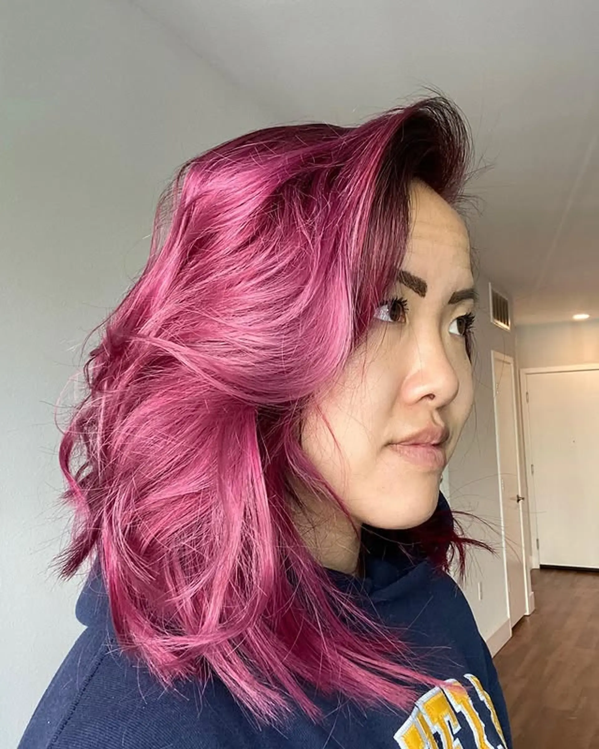 This medium-length wavy lob showcases a vibrant magenta and pink color, styled with voluminous, bouncy waves and a dramatic side-swept fringe for a playful yet chic appeal. 1