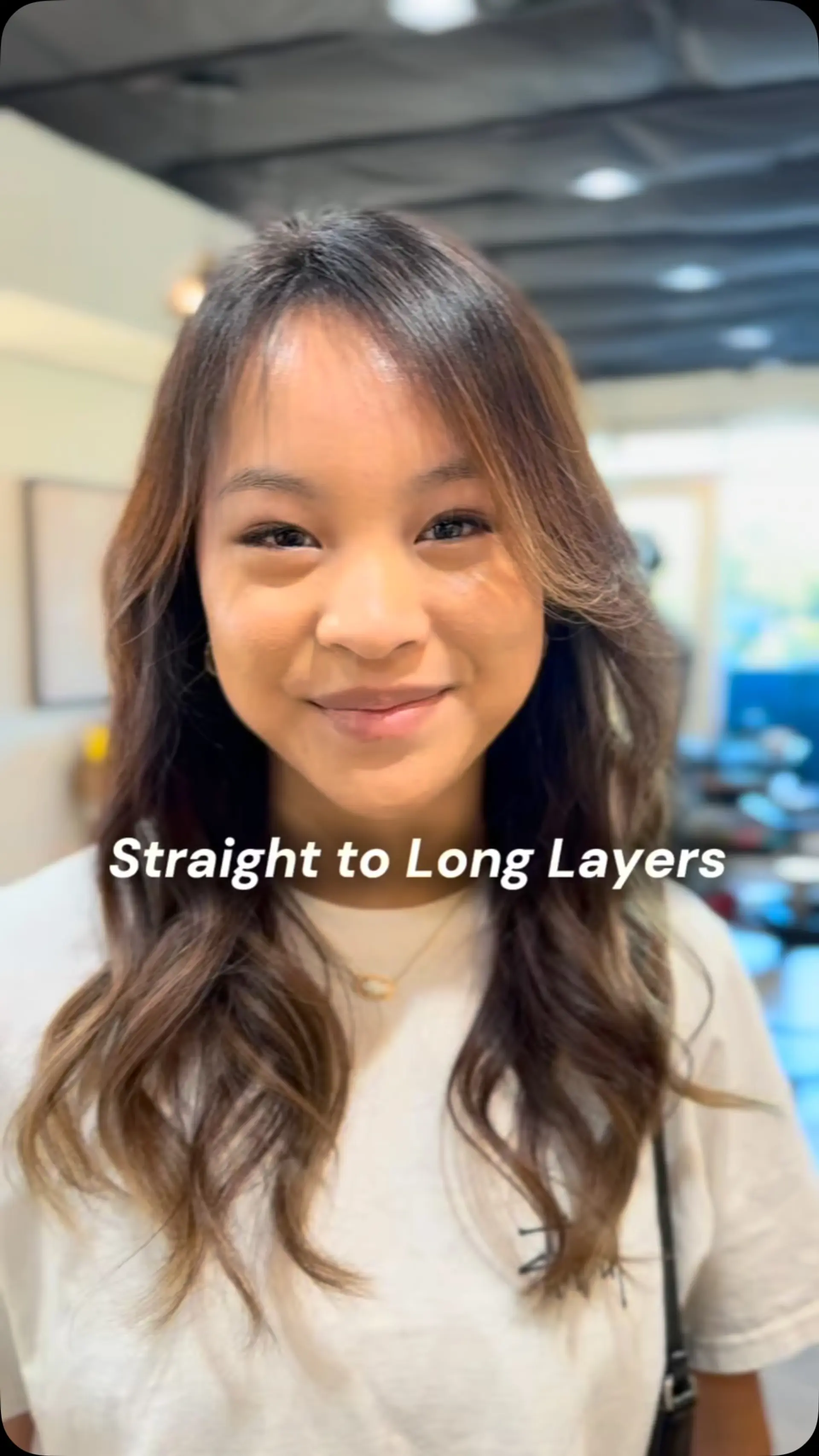 Long brown hair cut into flowing layers with soft face-framing pieces, wispy curtain bangs, and styled in gentle waves. 1