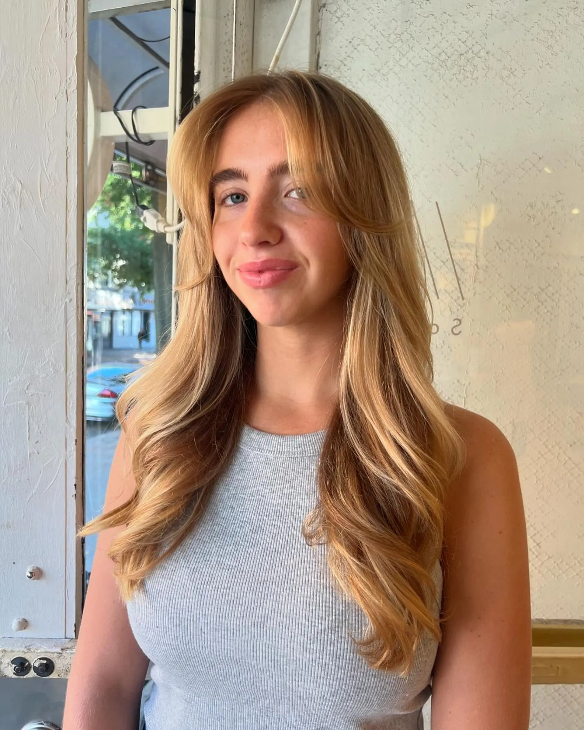 A long, wavy hairstyle with golden blonde color and face-framing layers, accentuating a harmonious flow and soft waves. 1