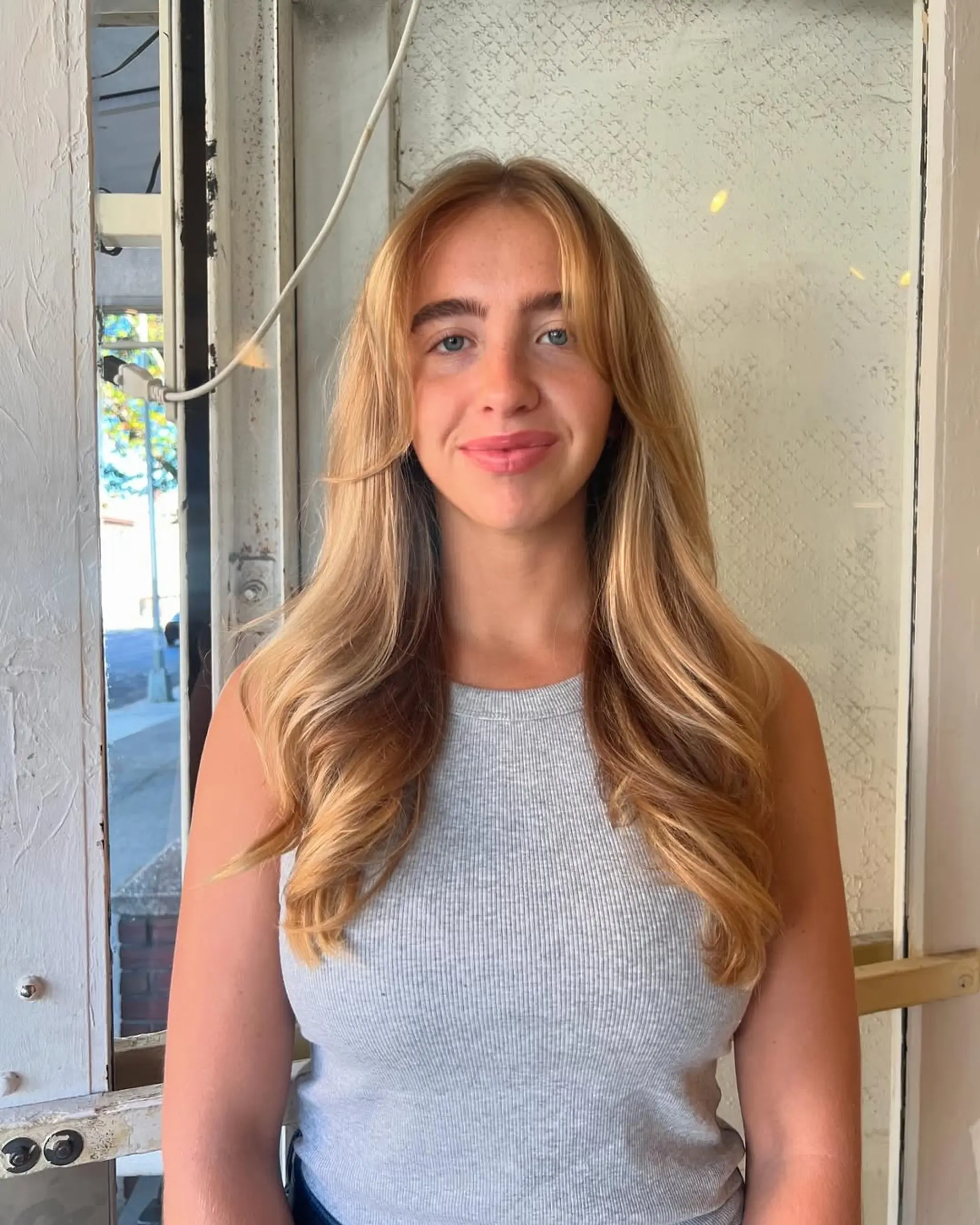 A long, wavy hairstyle with golden blonde color and face-framing layers, accentuating a harmonious flow and soft waves. 2