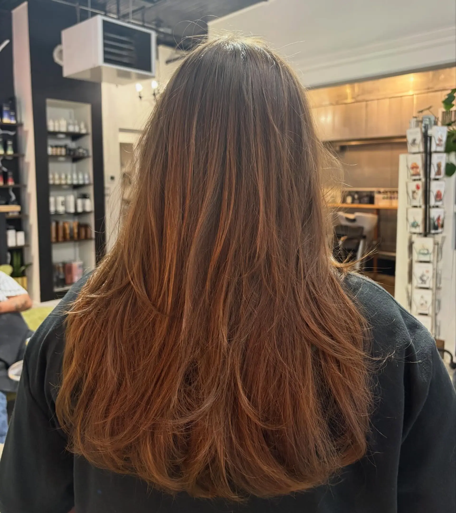 Long warm brown hair cut into soft, flowing layers with curled-under ends. 1