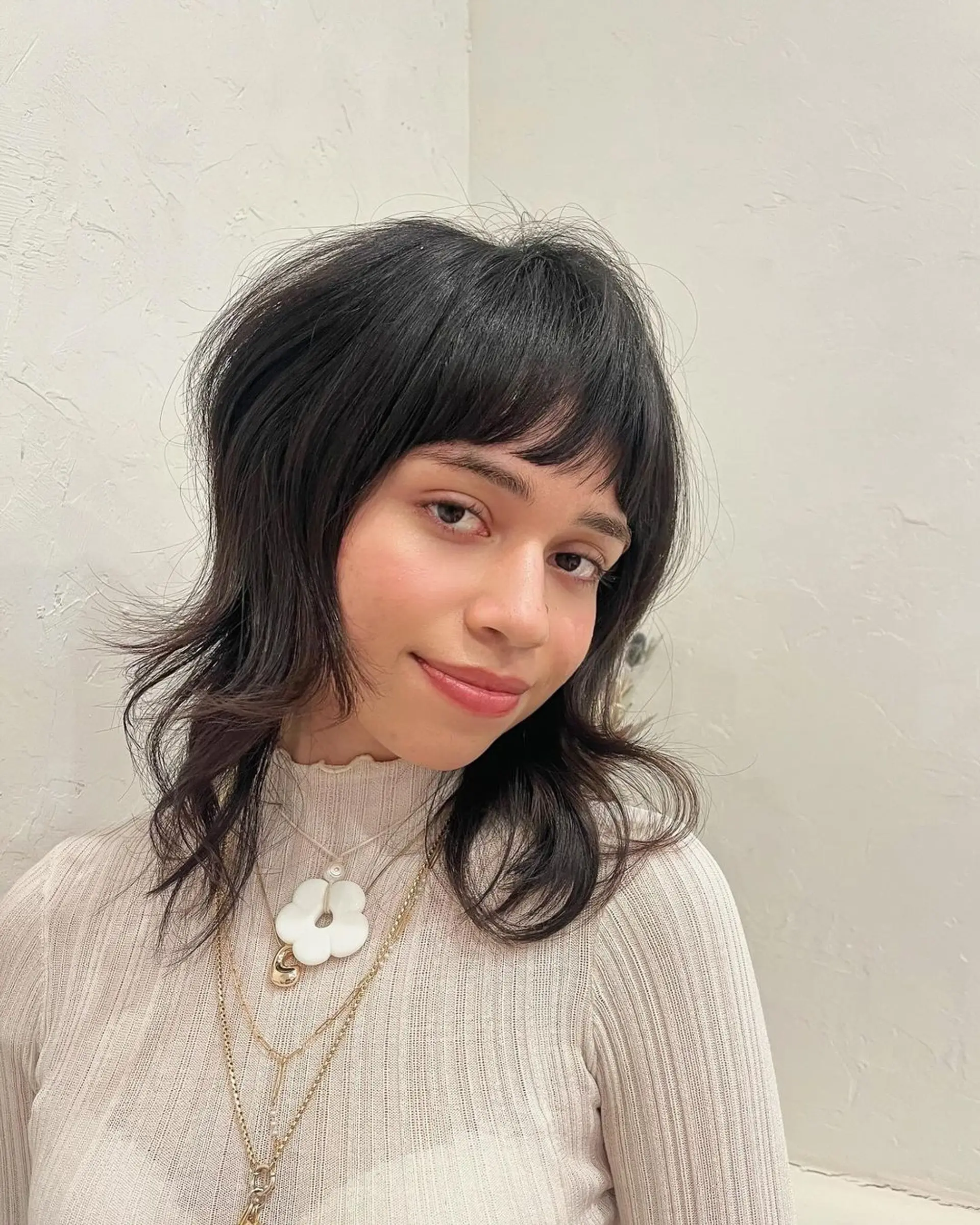 A modern shag cut with medium-length wavy black hair, characterized by layered fringe, face-framing layers, and textured ends. 1