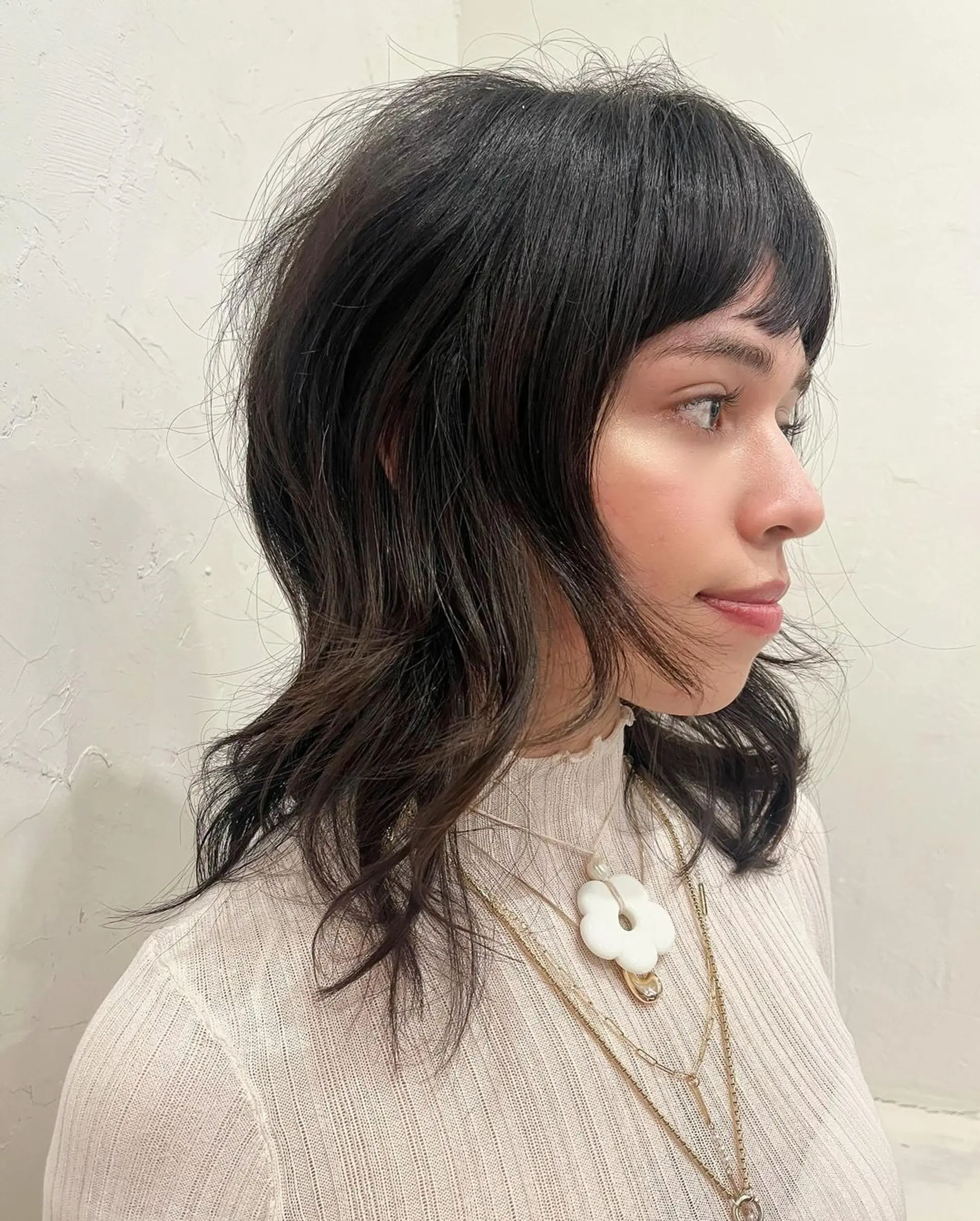 A modern shag cut with medium-length wavy black hair, characterized by layered fringe, face-framing layers, and textured ends. 2