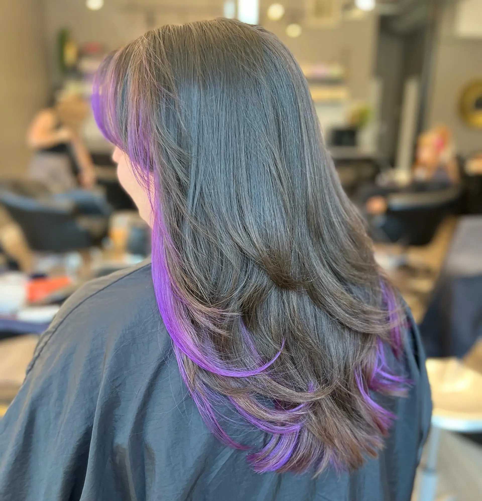 Long layered hairstyle with face-framing layers and vibrant purple highlights. 1