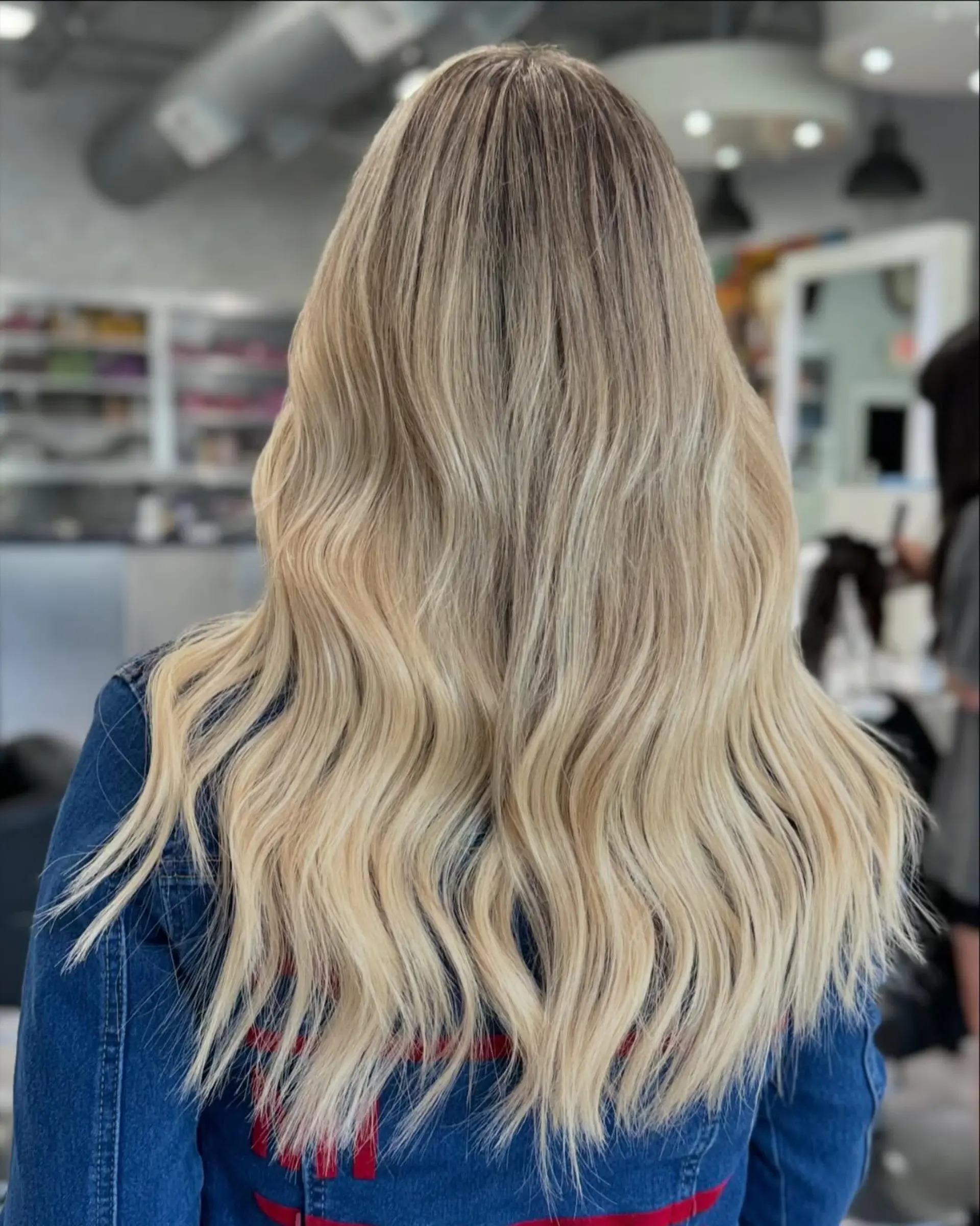 Long, wavy hair with a buttery blonde balayage and natural roots. 1