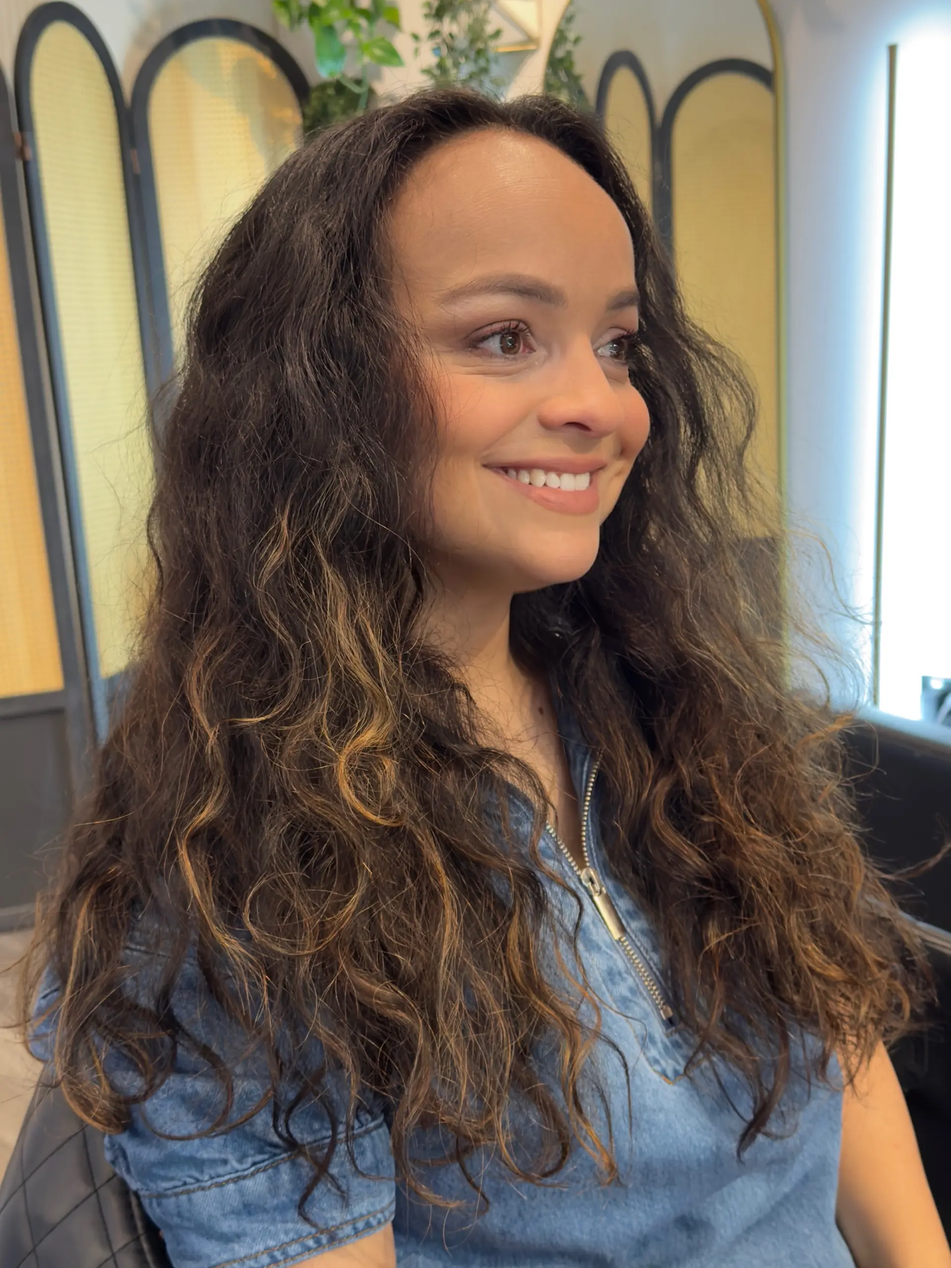 Long, flowing butterfly haircut cut in cascading layers to complement naturally curly and wavy brunette hair. 1