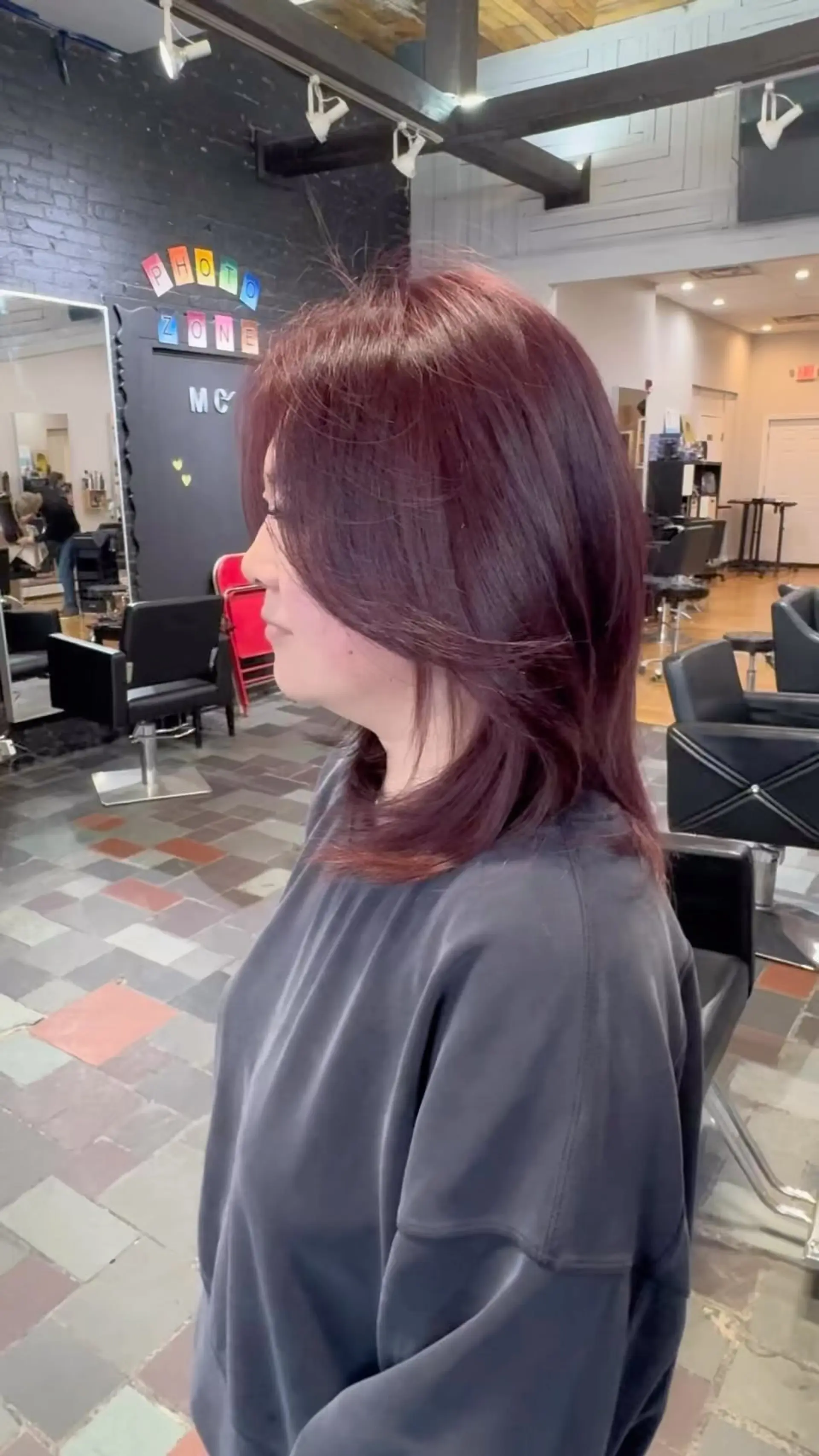 Medium-length haircut with face-framing layers and smooth blowout styling in a vibrant plum burgundy tone. 1