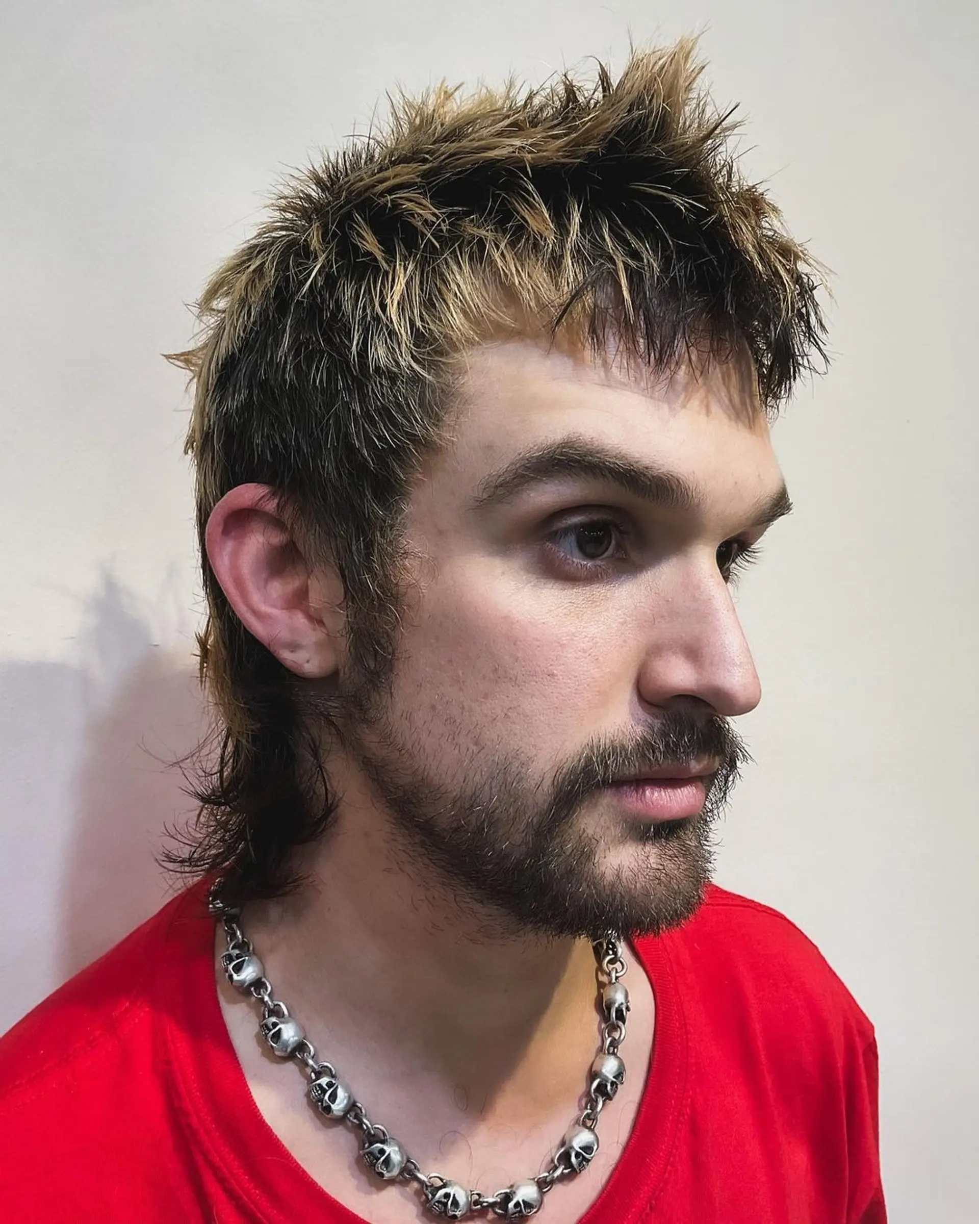 A daring spiky top with dark brown base and blonde highlights, merging into a feathered mullet with choppy layers and a textured, wavy finish. 1