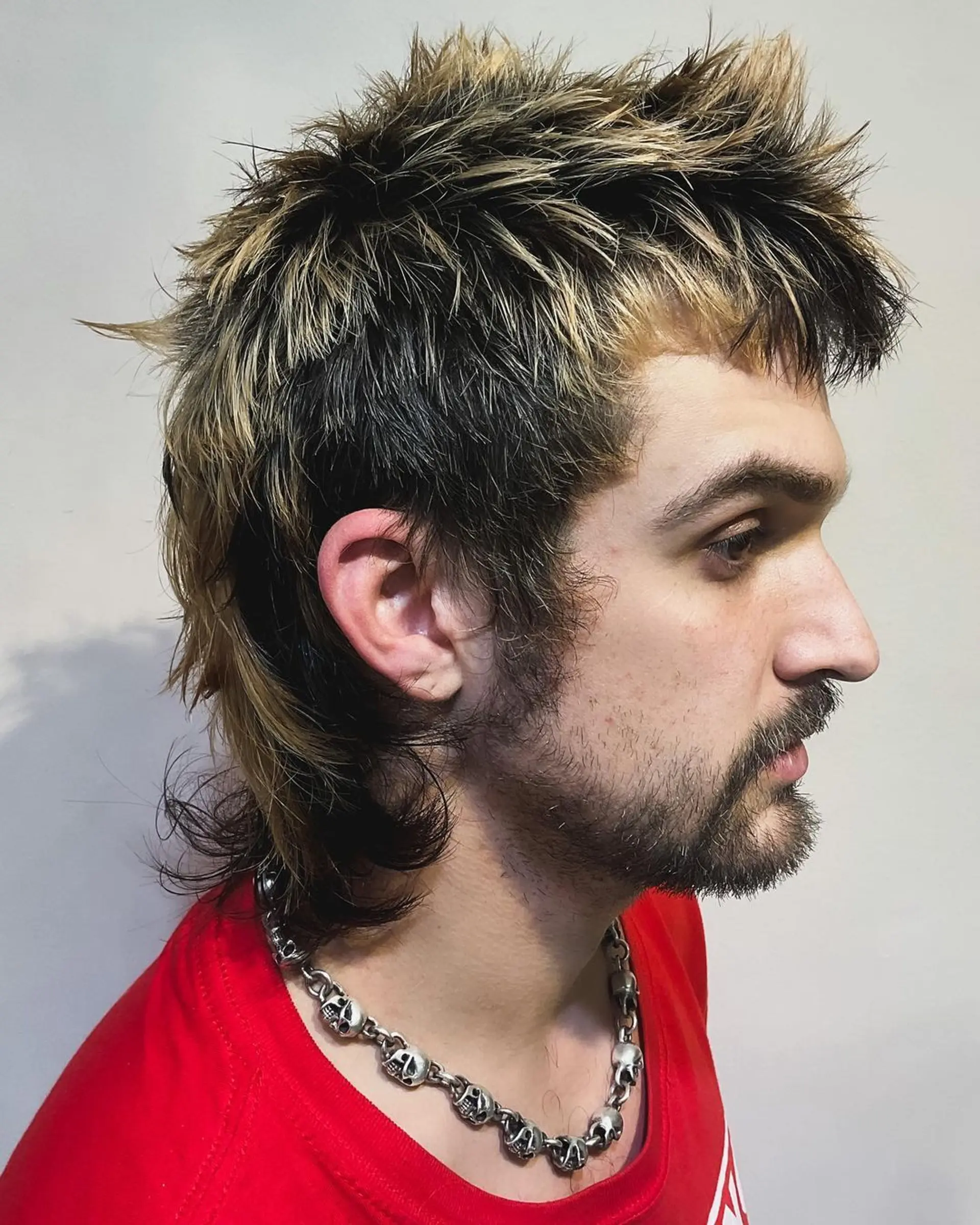 A daring spiky top with dark brown base and blonde highlights, merging into a feathered mullet with choppy layers and a textured, wavy finish. 2