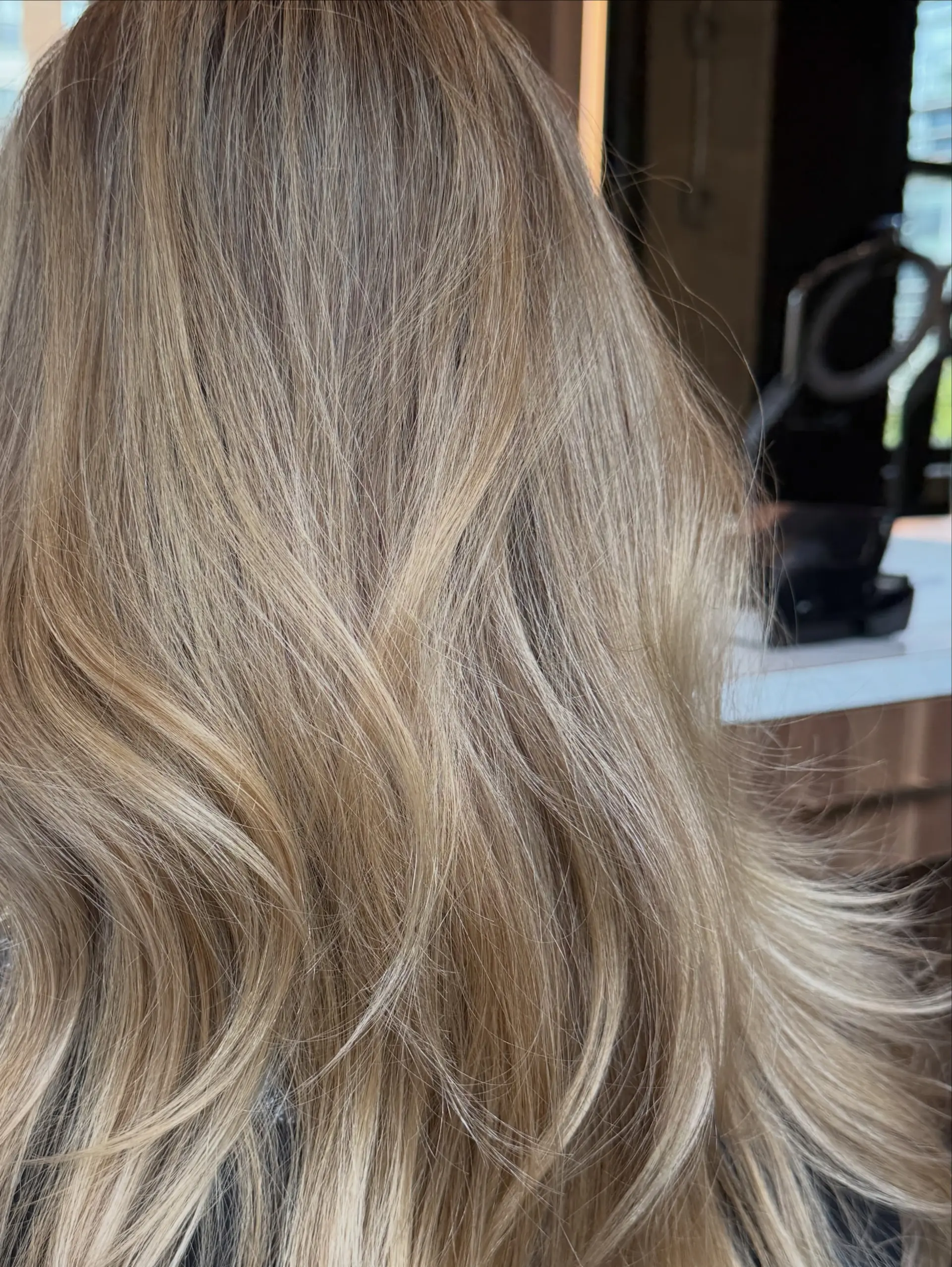 A multi-tonal, seamless blonde highlight look styled in soft, flowing blow-dry waves. 1