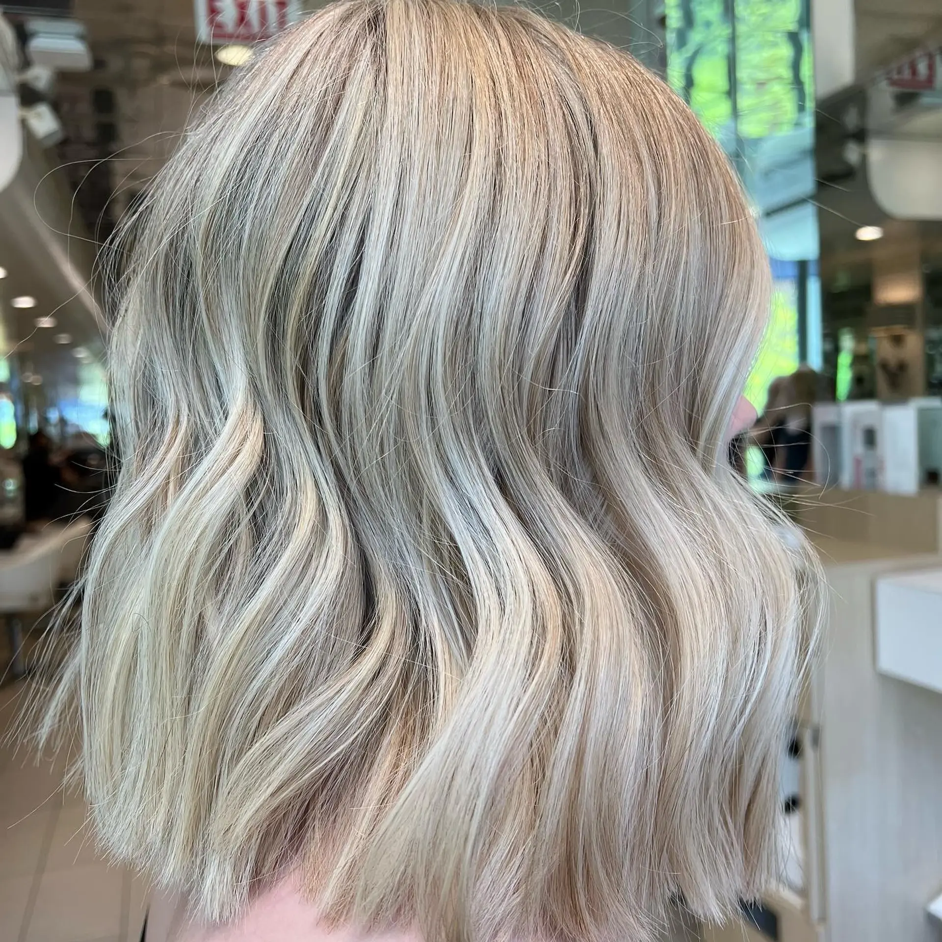 A blunt, collar-length bob styled with soft, effortless waves and cool-toned blonde highlights. 1