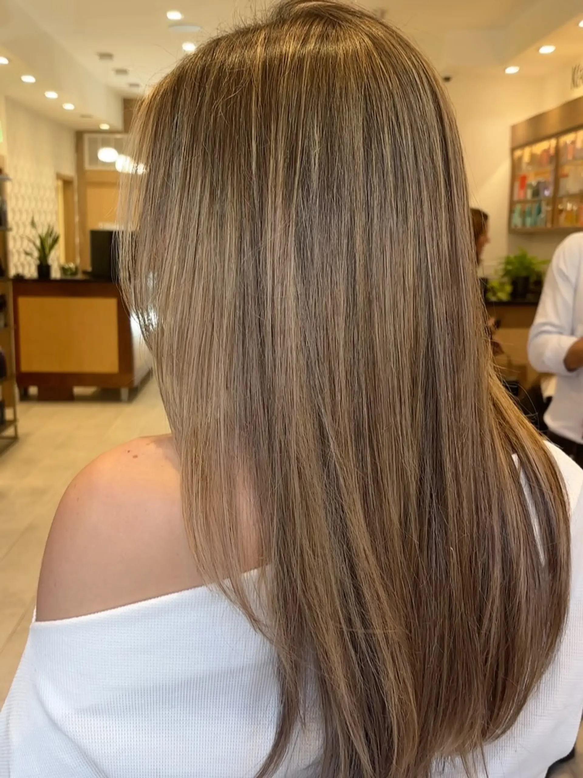 Long straight hair featuring soft, blended bronde and honey-toned highlights for a warm dimensional look. 1