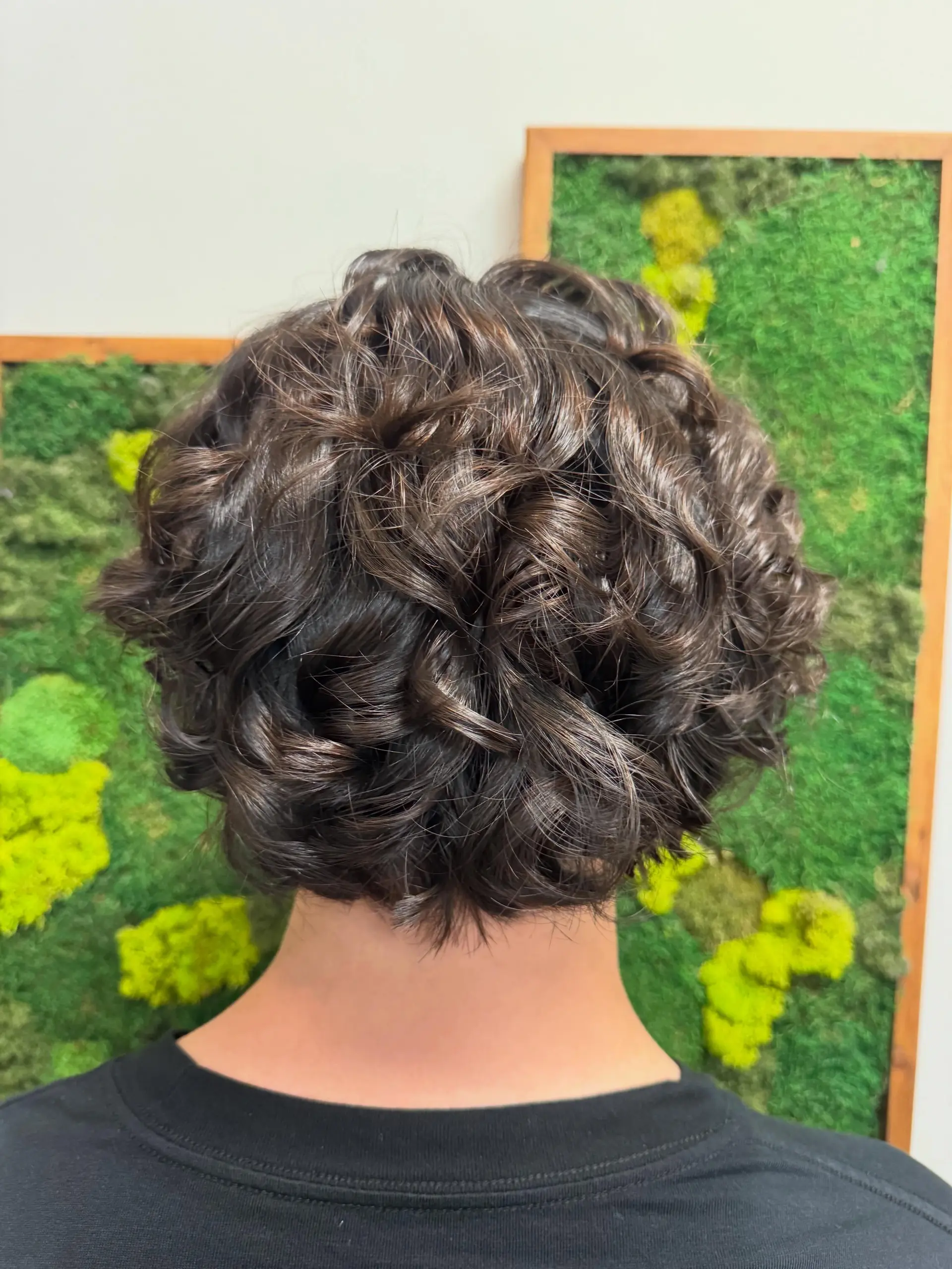 A short, defined curly style featuring voluminous permed texture throughout the crown and nape. 1