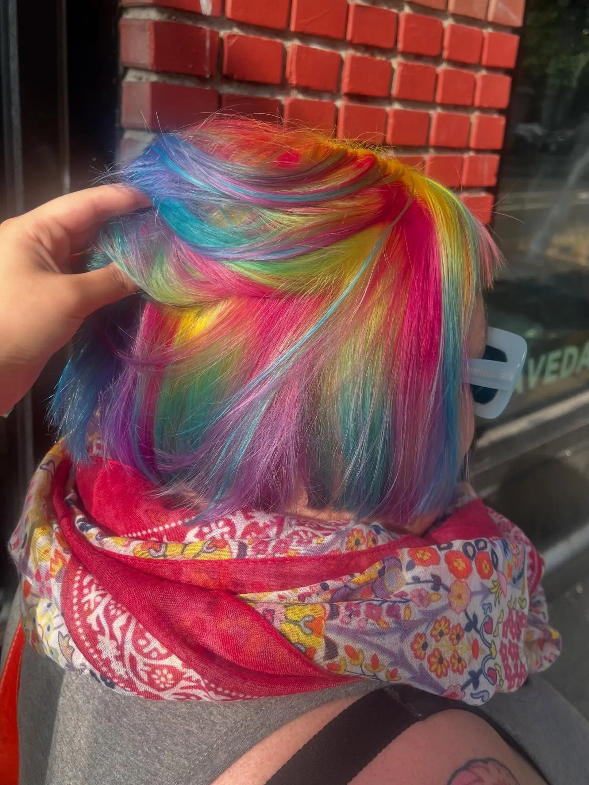 A sleek short bob featuring multi-tonal rainbow vivid hair colors with shades of pink, yellow, blue, and purple. 1