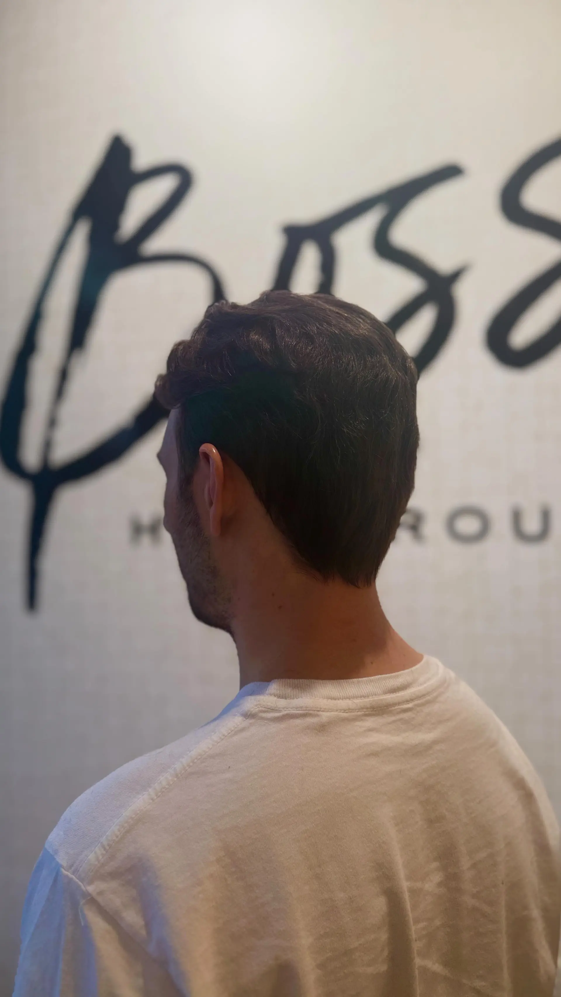 A clean, classic men's haircut featuring softly tapered sides and back with natural wave and texture on top. 1