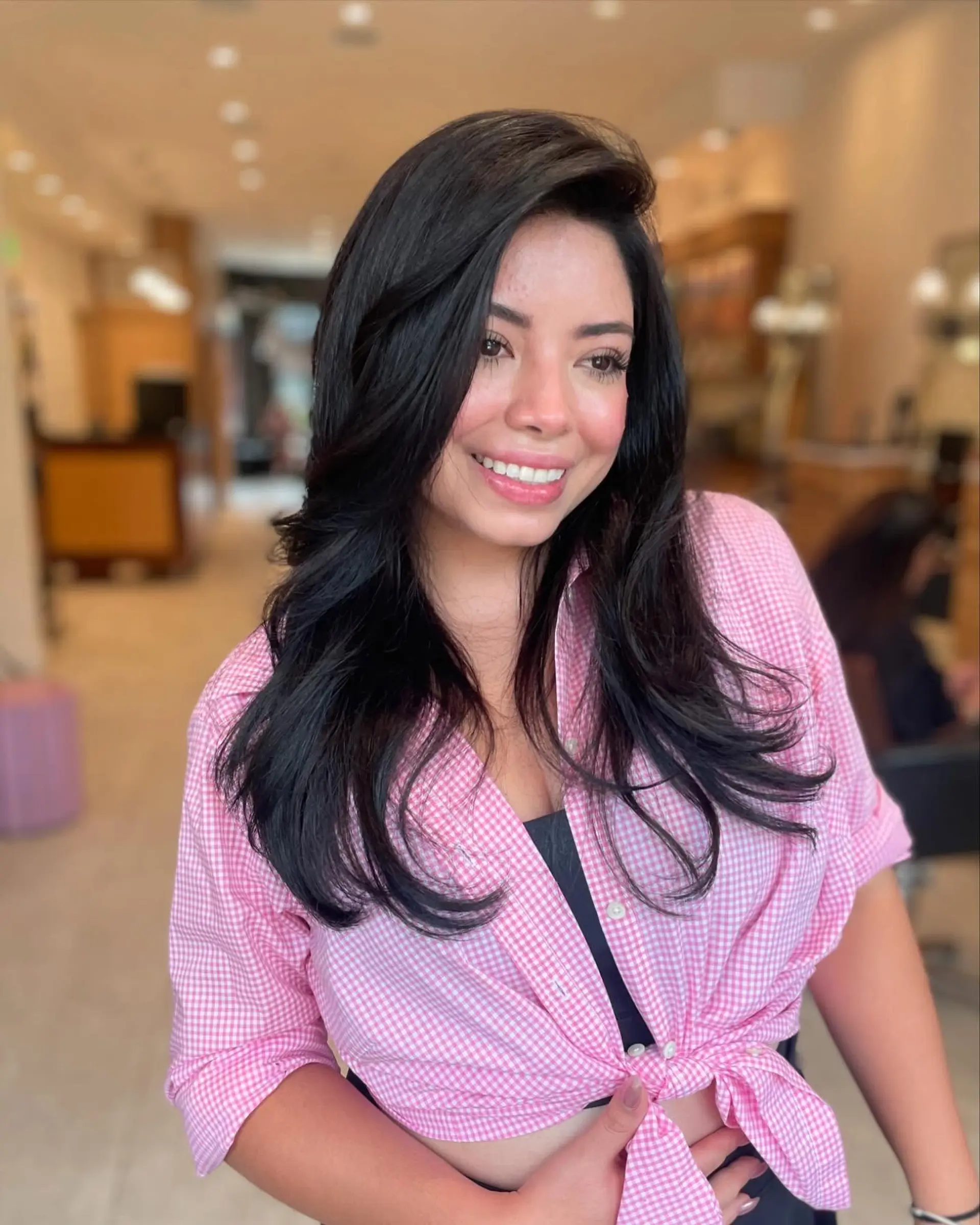 Long jet black hair styled in a voluminous layered blowout with a deep side part and soft curved ends. 1