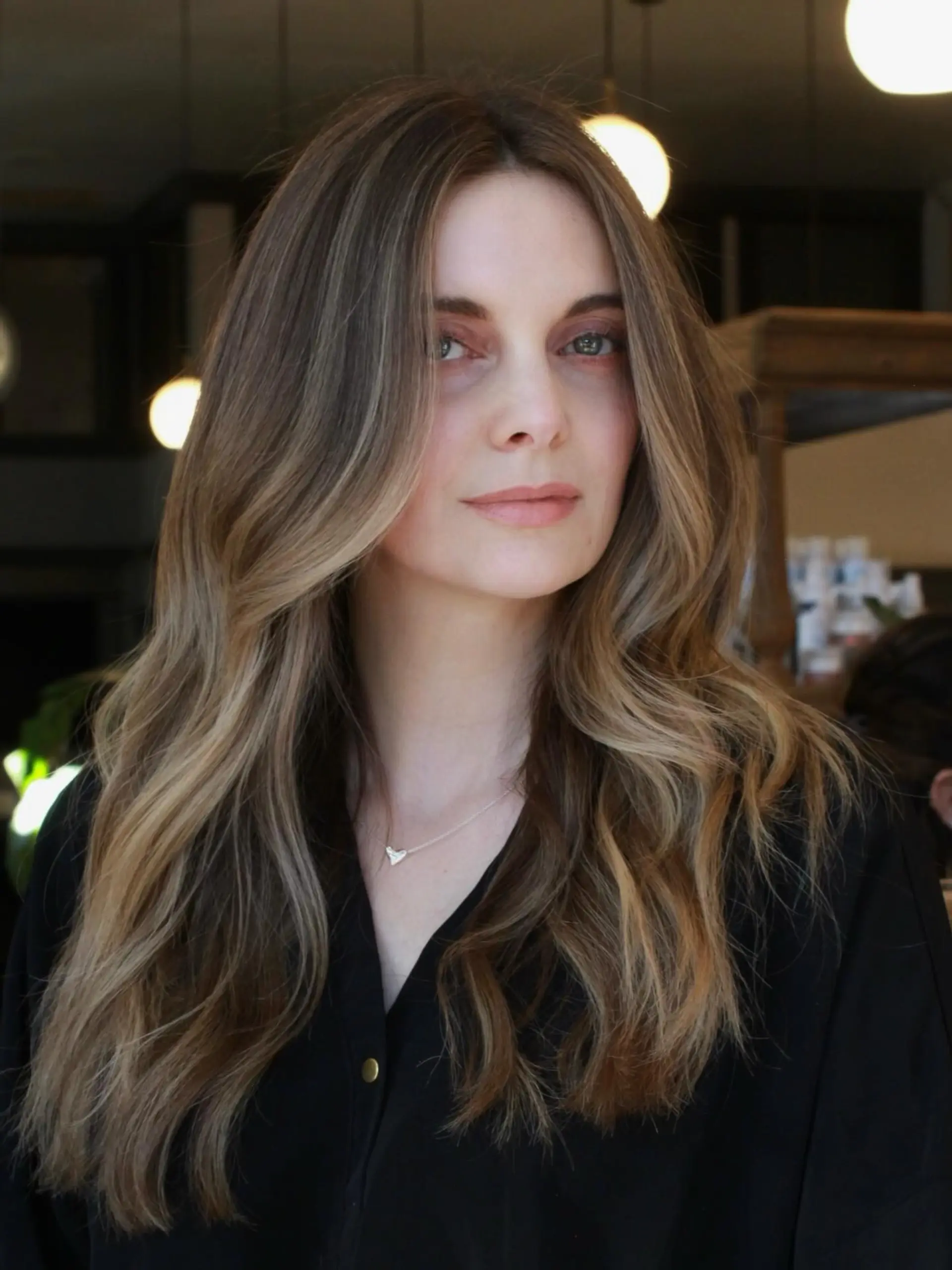 Long dimensional ash blonde and light brown hair styled into soft, flowing blowout waves. 1