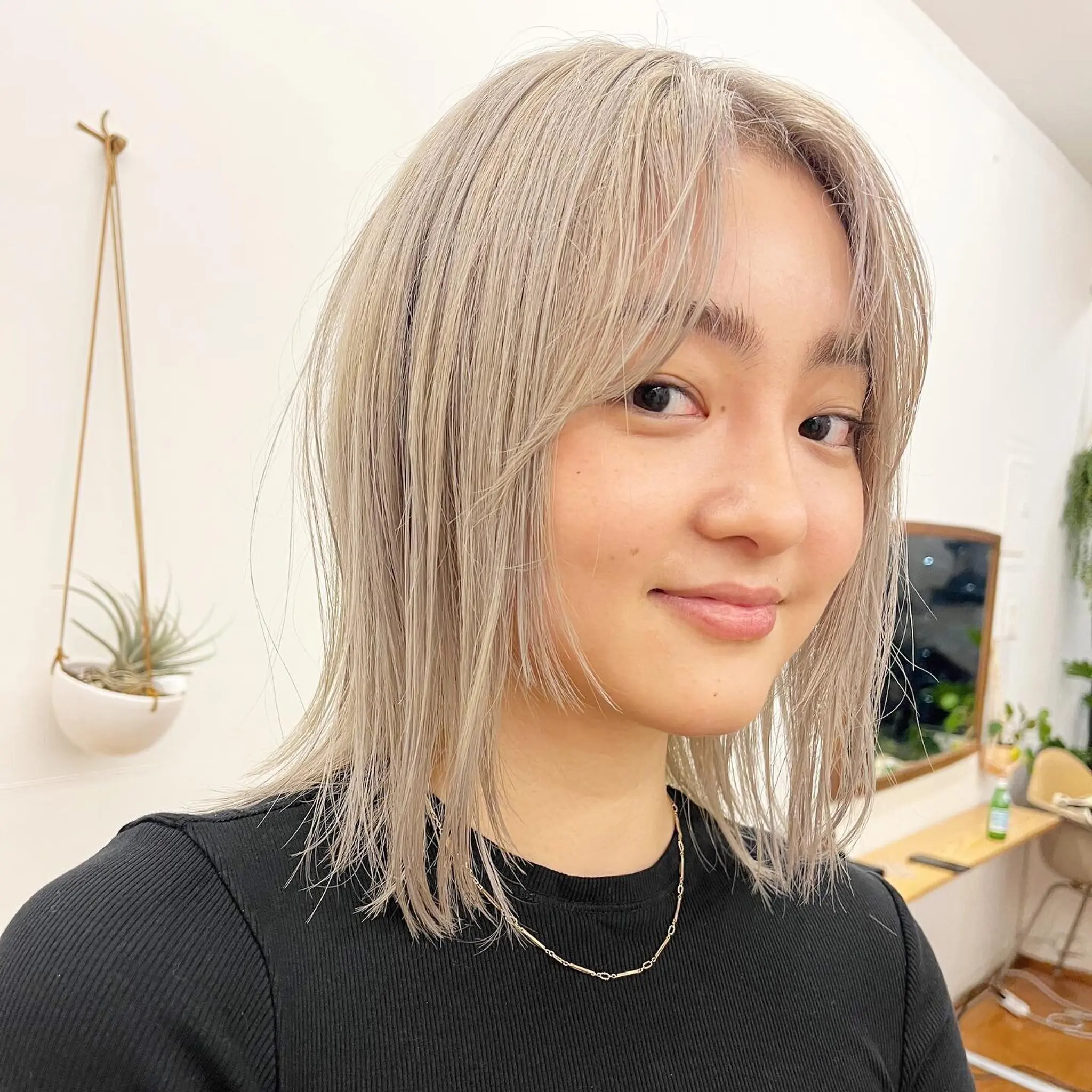 This medium-length, straight hairstyle has platinum blonde and silver tones, with soft layers, curtain bangs, and textured, razored edges for a chic and modern appearance. by @kotarohair.newyork