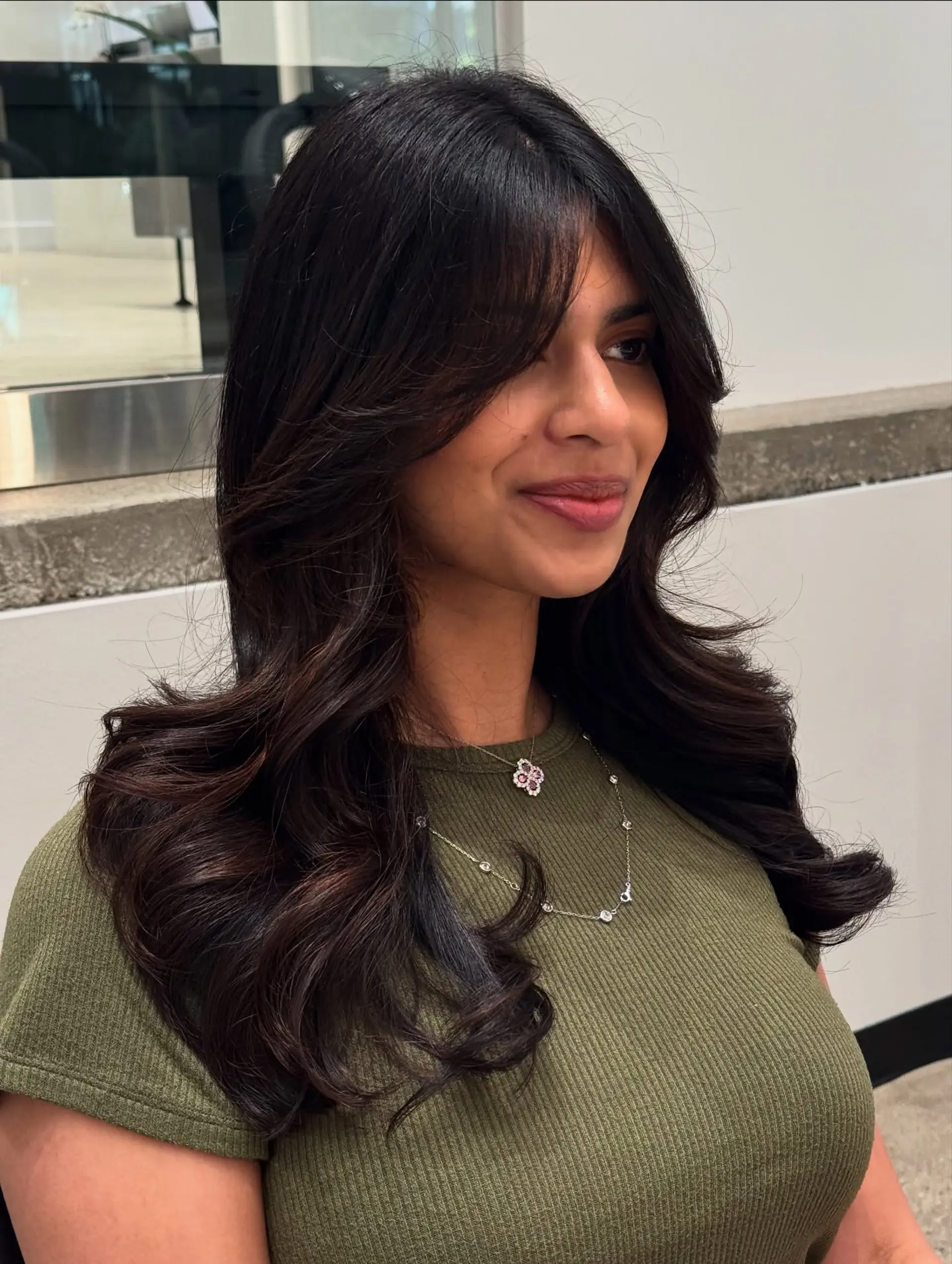 This hairstyle features long, soft waves with curtain bangs and face-framing layers. 1