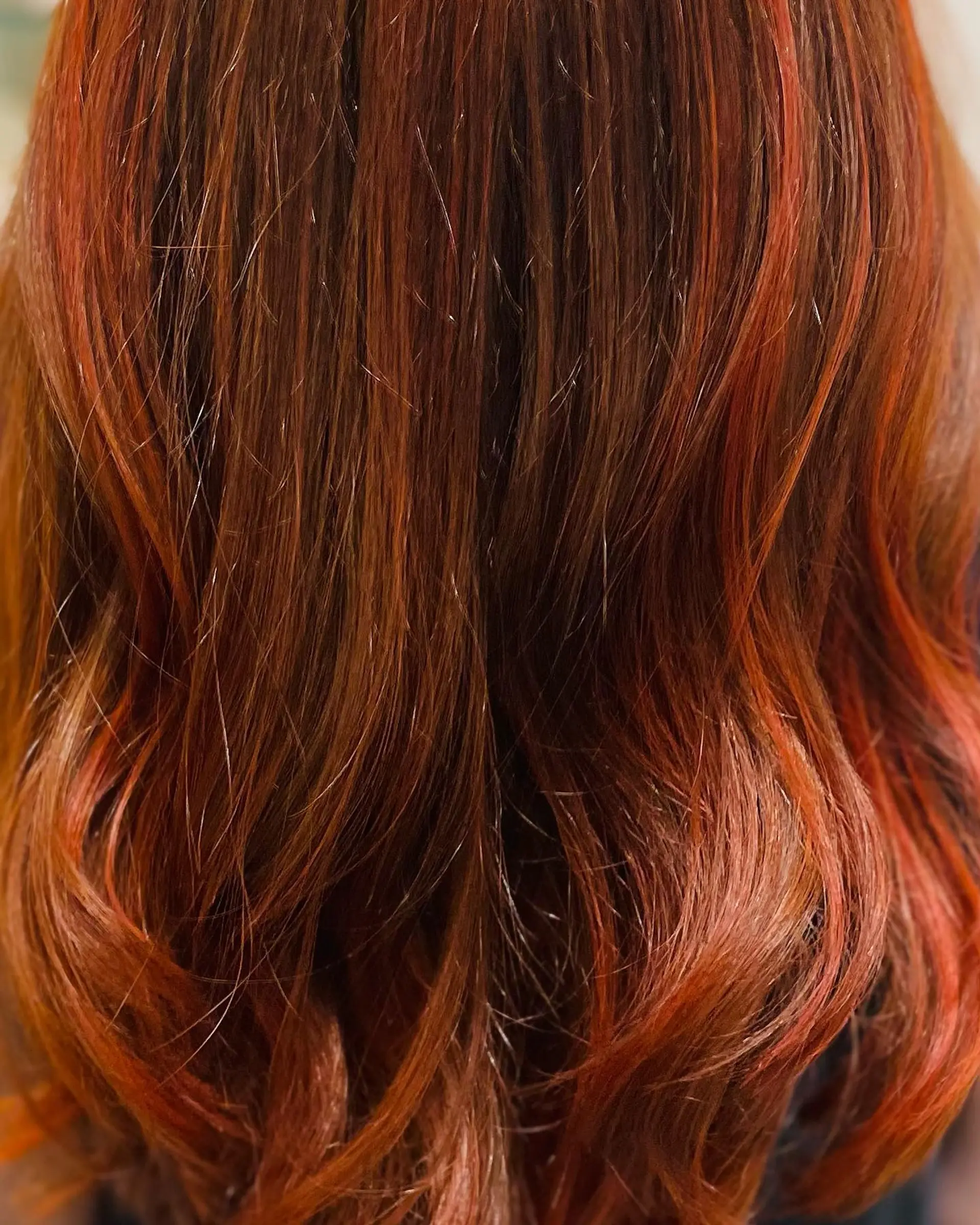 Rich autumn red balayage blending warm auburn base tones with vibrant copper and red highlights, styled in soft waves. 1