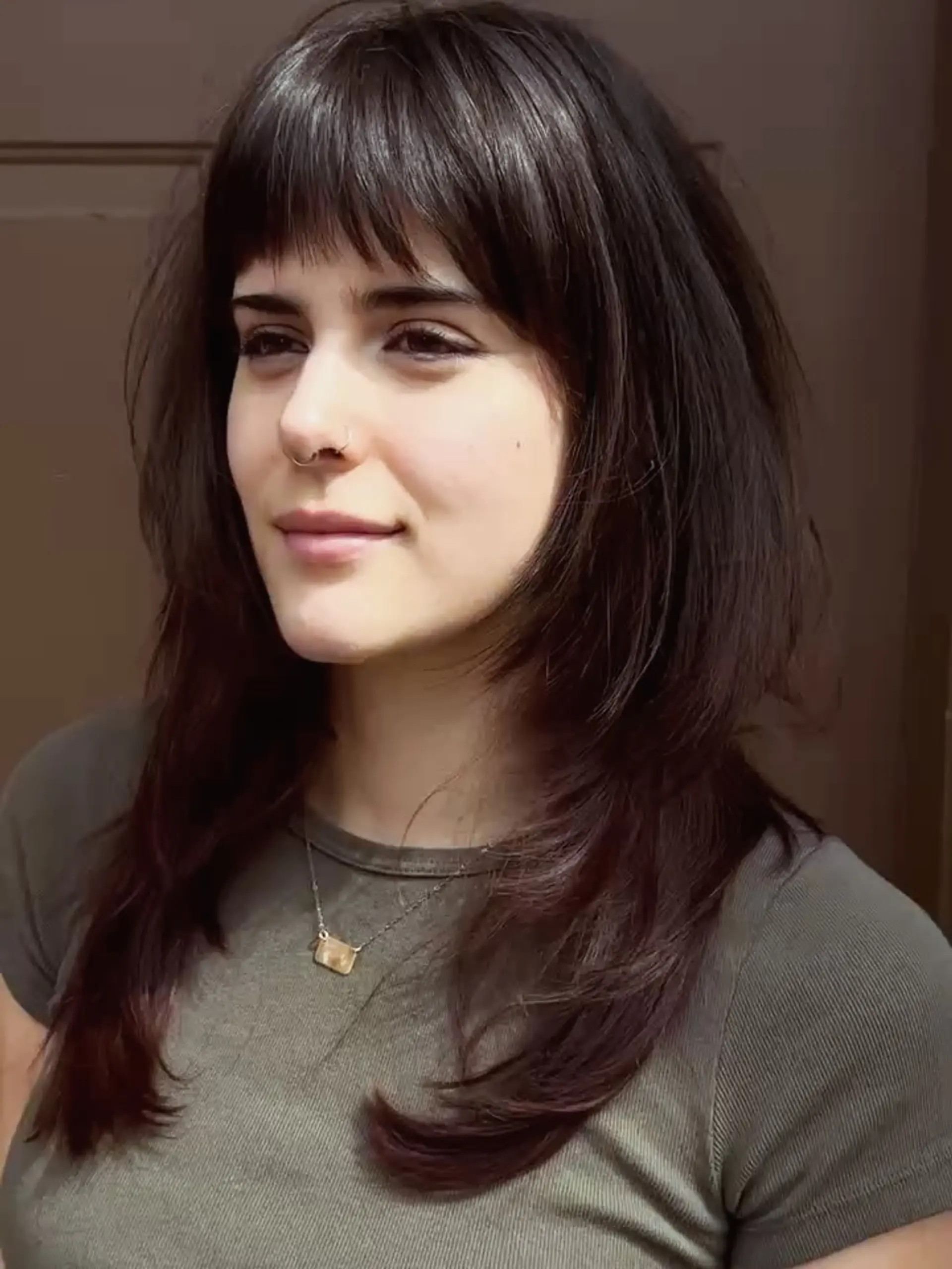 A layered, textured wolf cut featuring straight fringe bangs and feathered, face-framing layers. 1