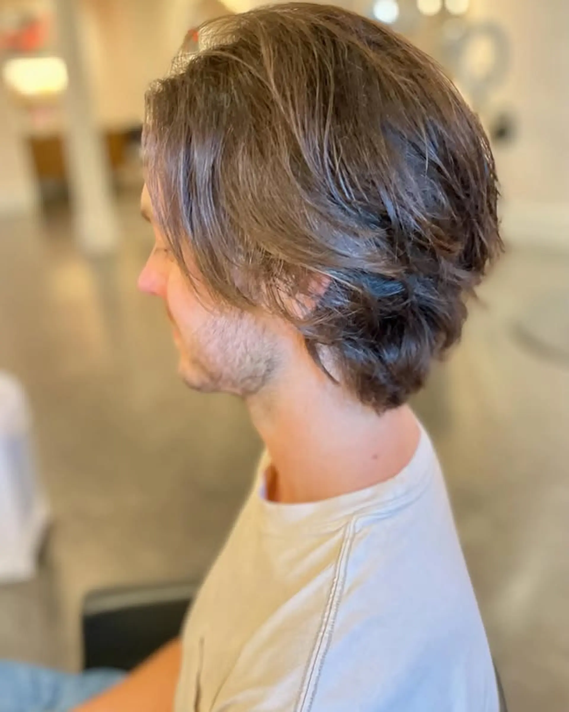 A versatile medium-length haircut with strategic layering to enhance natural texture and create a relaxed, 'flow' aesthetic. It's designed for easy styling and a casual, modern look with natural waves. 1