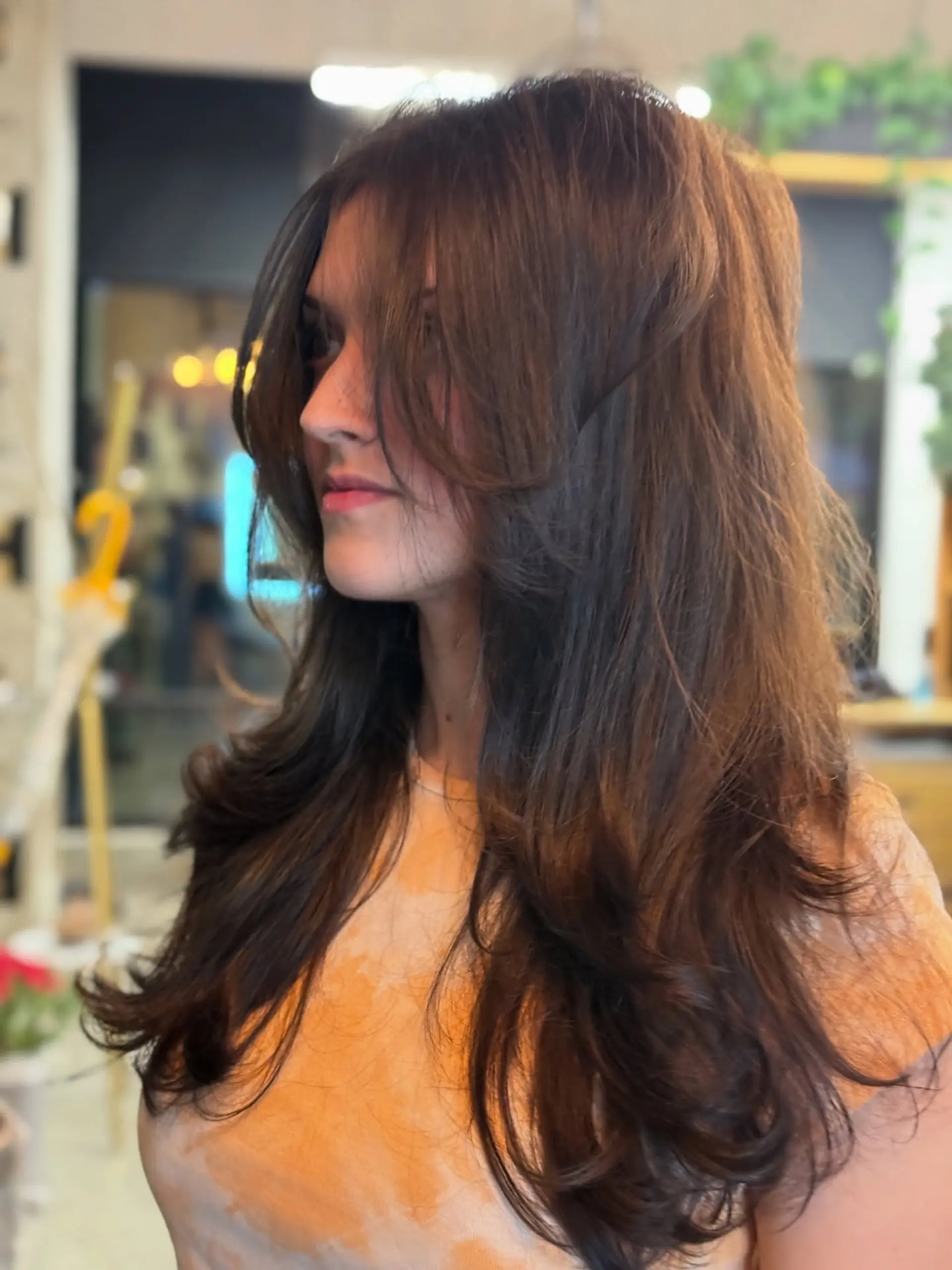 Long dark brown hair cut with soft face-framing curtain bangs and voluminous layers. 1