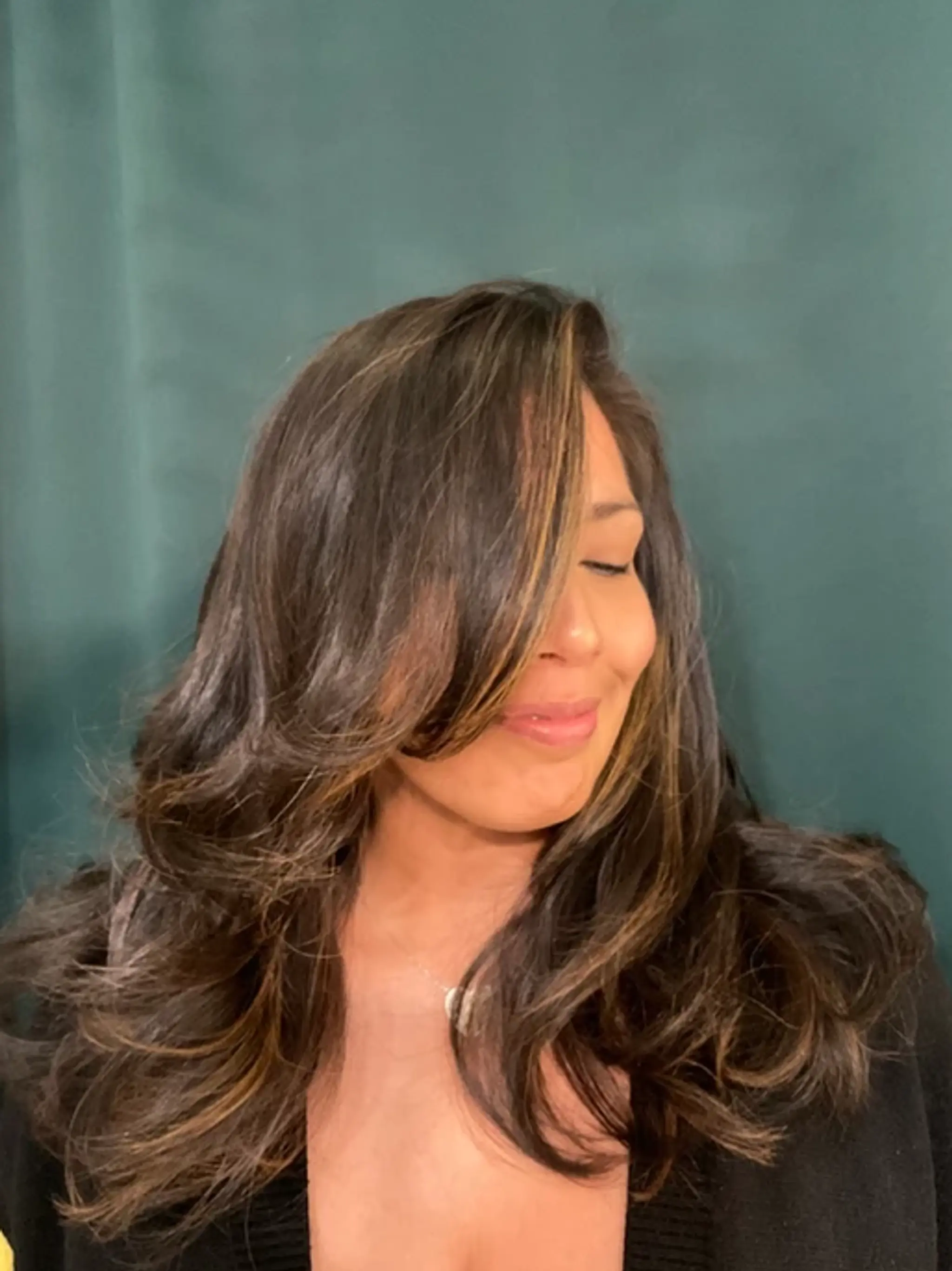 Long, wavy dark brown hair with honey blonde highlights, styled with face-framing layers and a side part for a natural, voluminous look.