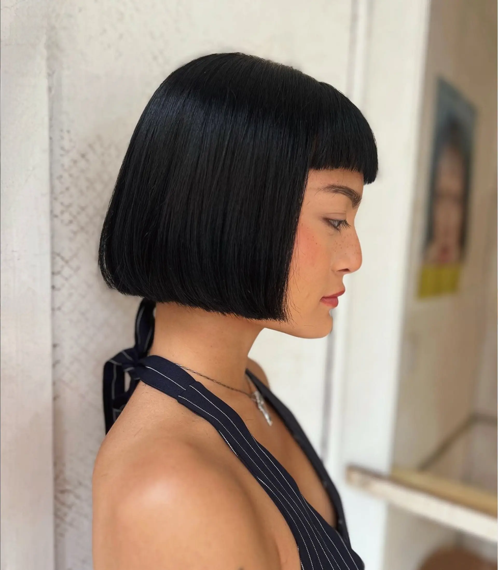 A sleek, black short bob with blunt bangs and a glossy finish, styled in a precise, face-framing cut. 1