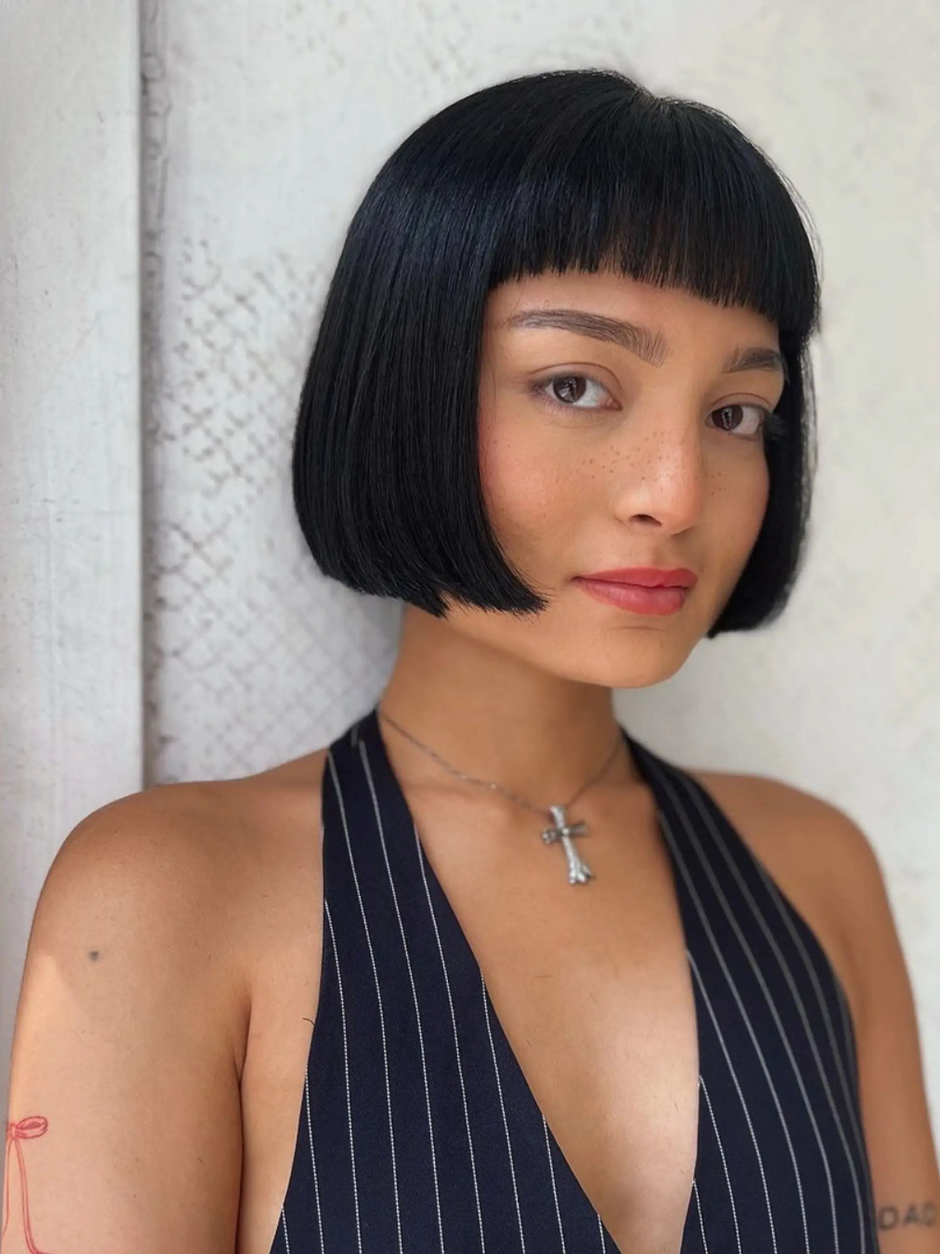 A sleek, black short bob with blunt bangs and a glossy finish, styled in a precise, face-framing cut. 2