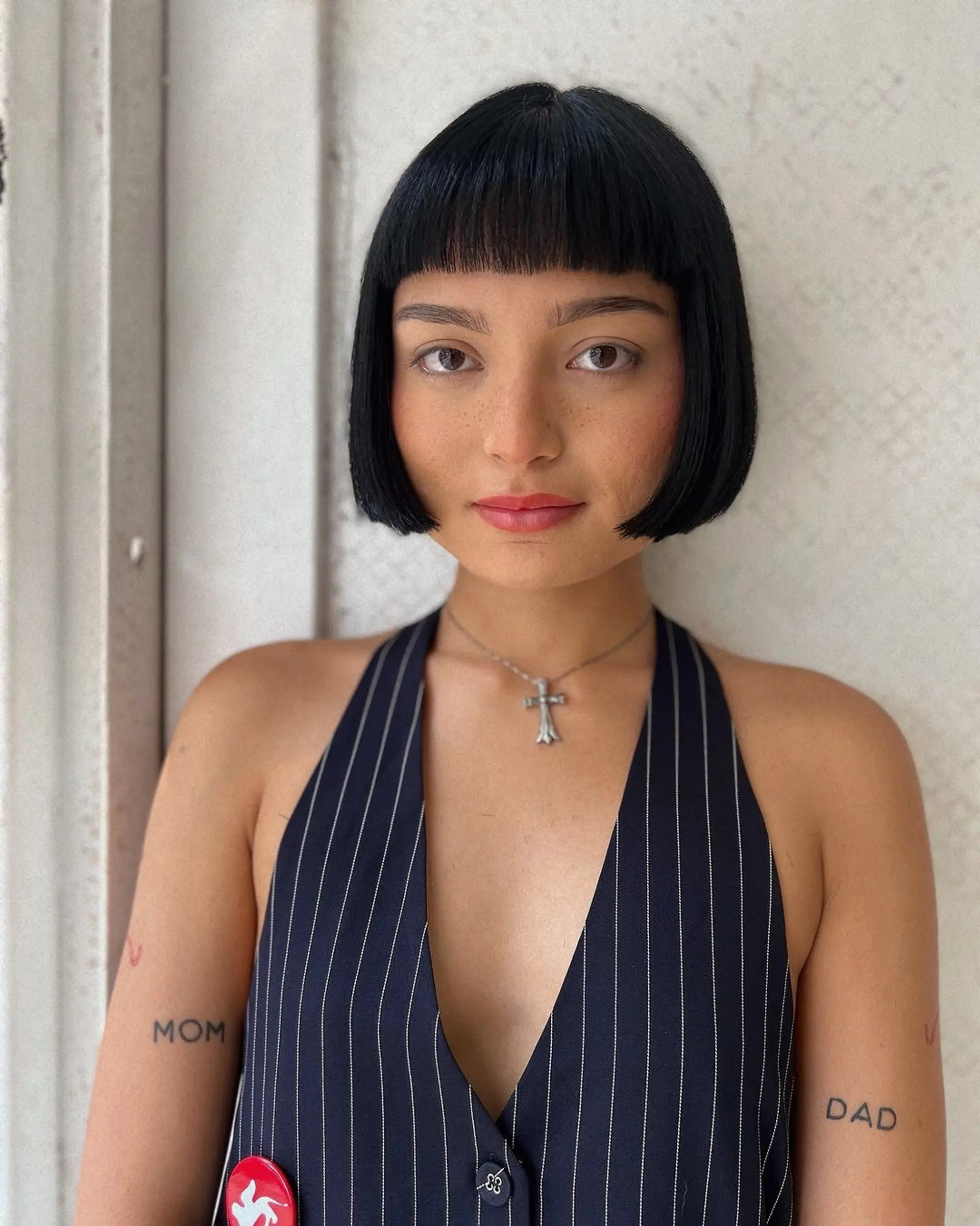A sleek, black short bob with blunt bangs and a glossy finish, styled in a precise, face-framing cut. 3