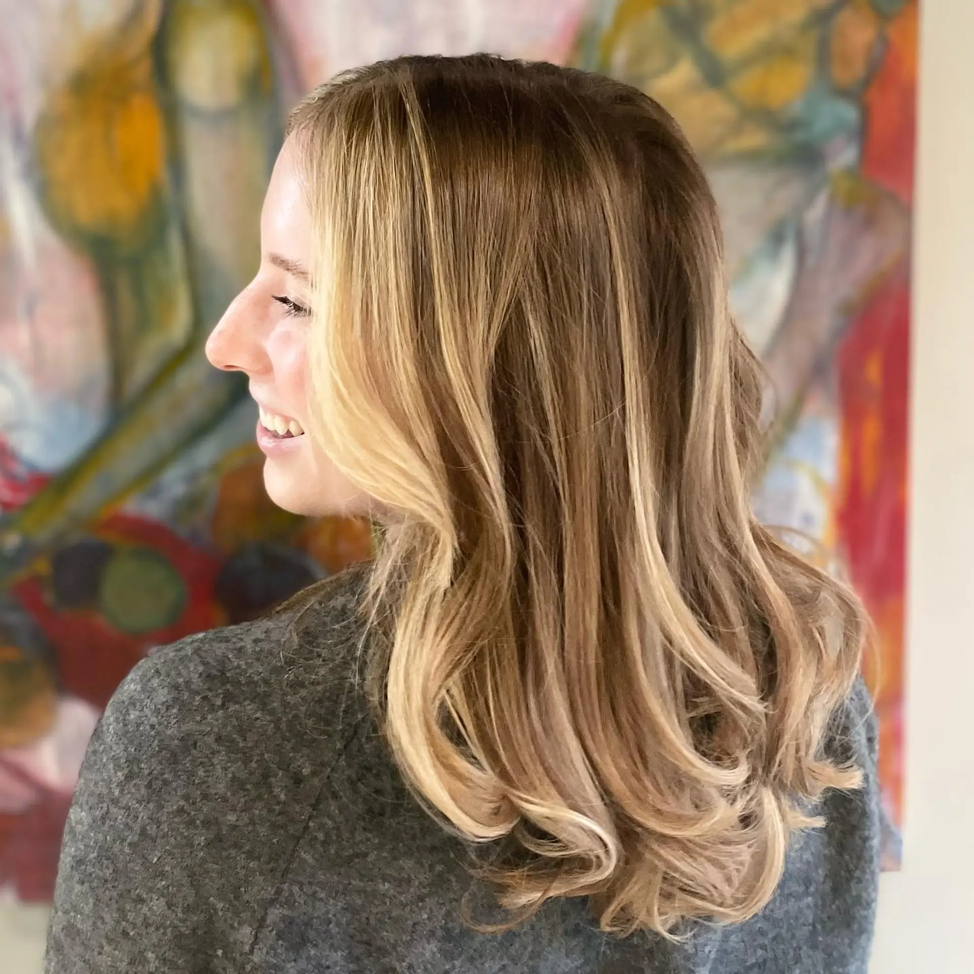 Medium-length light brown hair enhanced with bright face-framing blonde highlights and soft, bouncy curled ends. 1