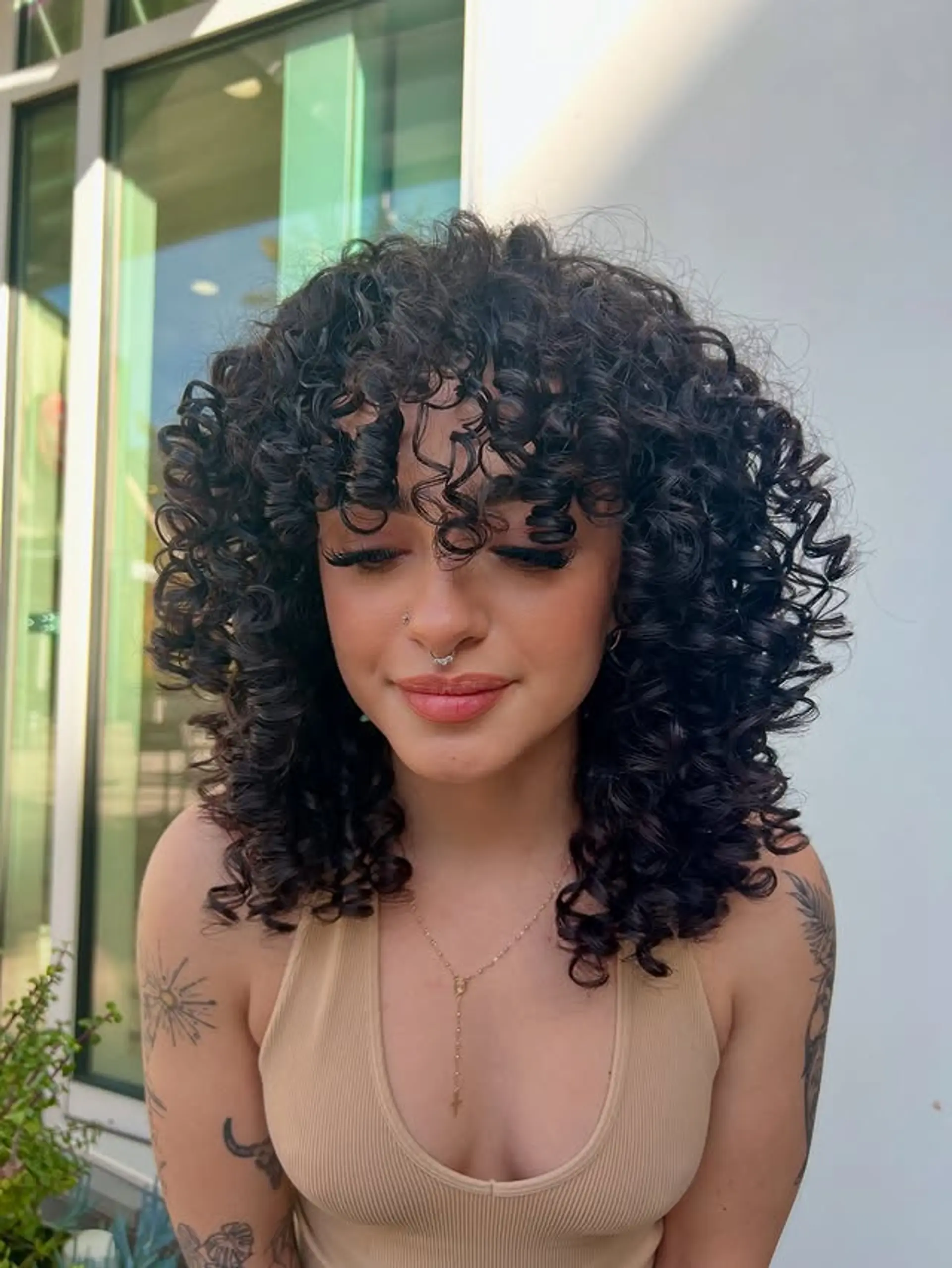 A stylish curly shag with bangs designed to enhance natural texture and volume. 1