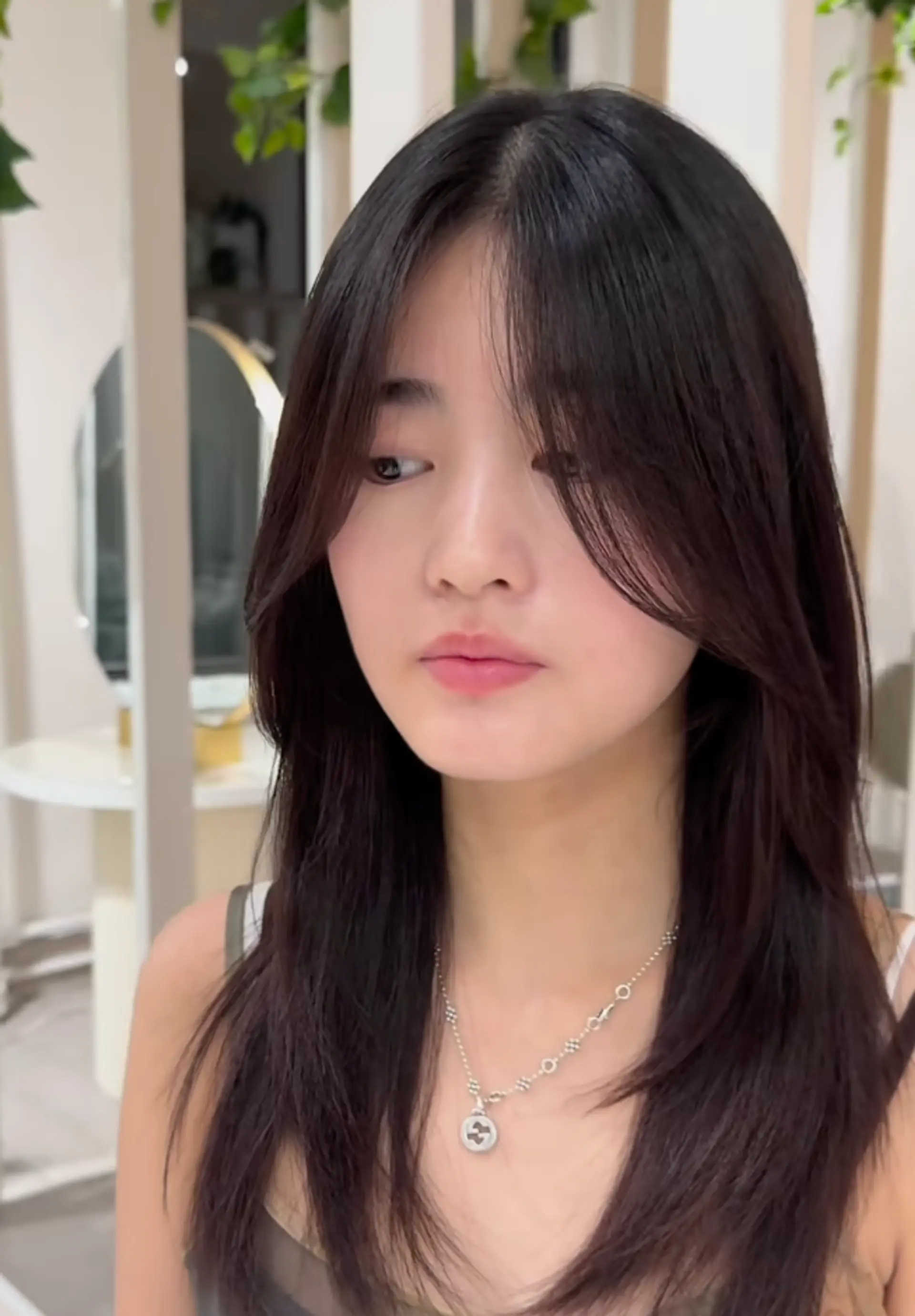 Medium-length dark brown hair with a layered cut, face-framing layers, and side-swept bangs. 1