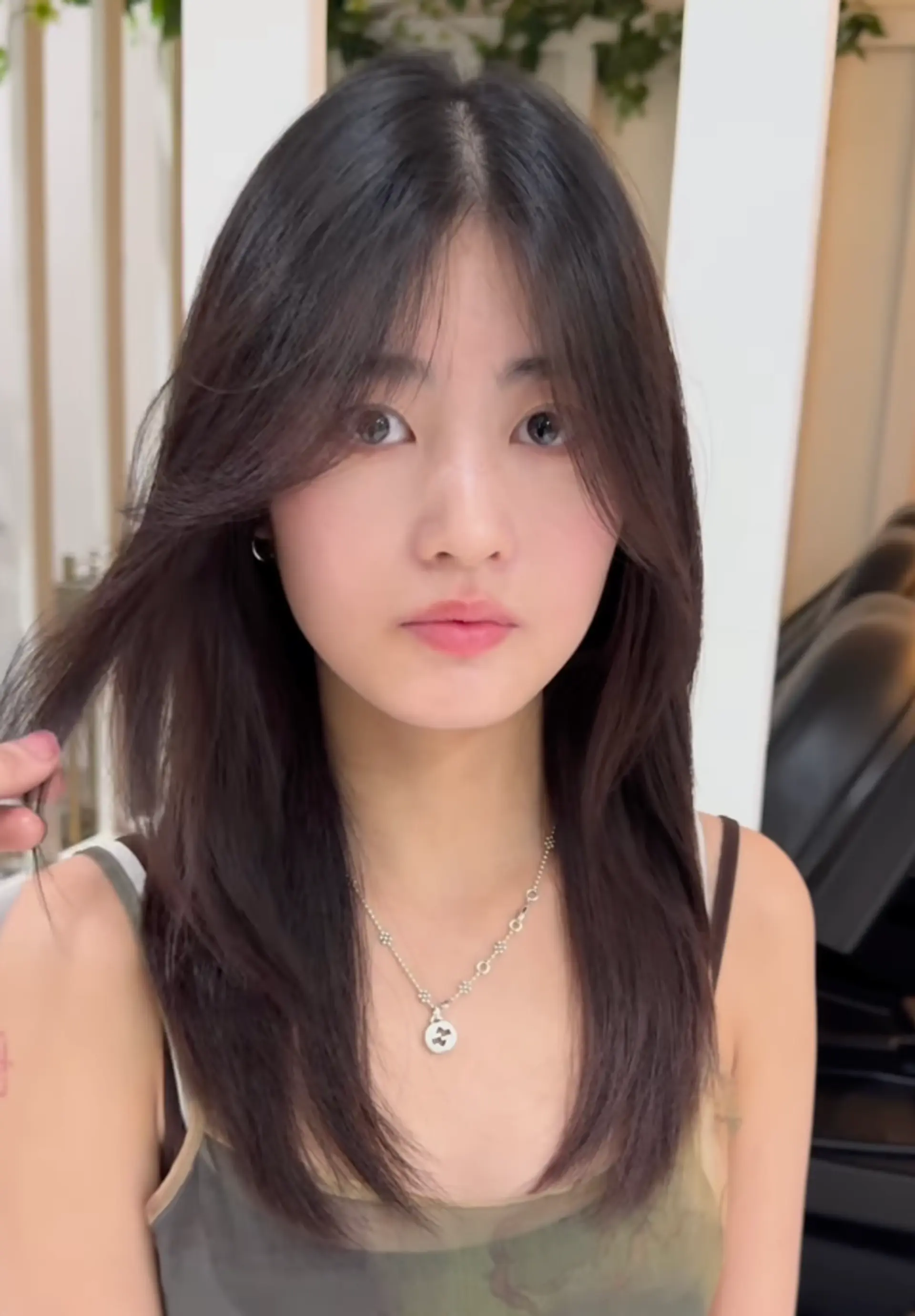 Medium-length dark brown hair with a layered cut, face-framing layers, and side-swept bangs. 2