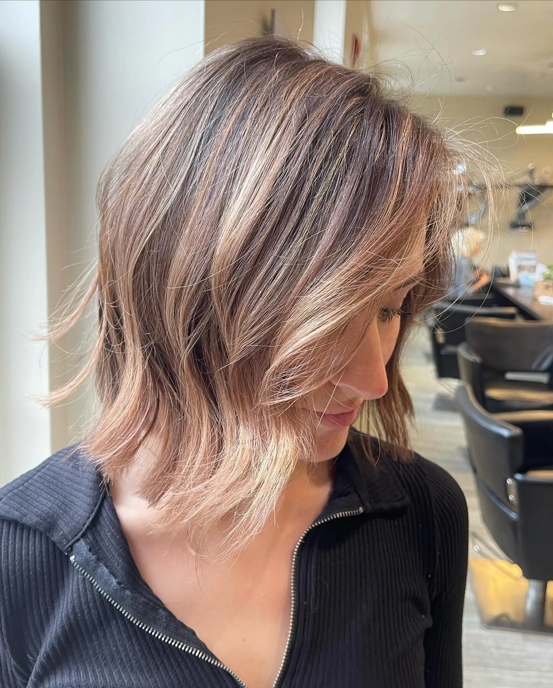 A textured neck-length bob styled with soft, piecey waves and dimensional caramel blonde highlights over a light brown base. 1