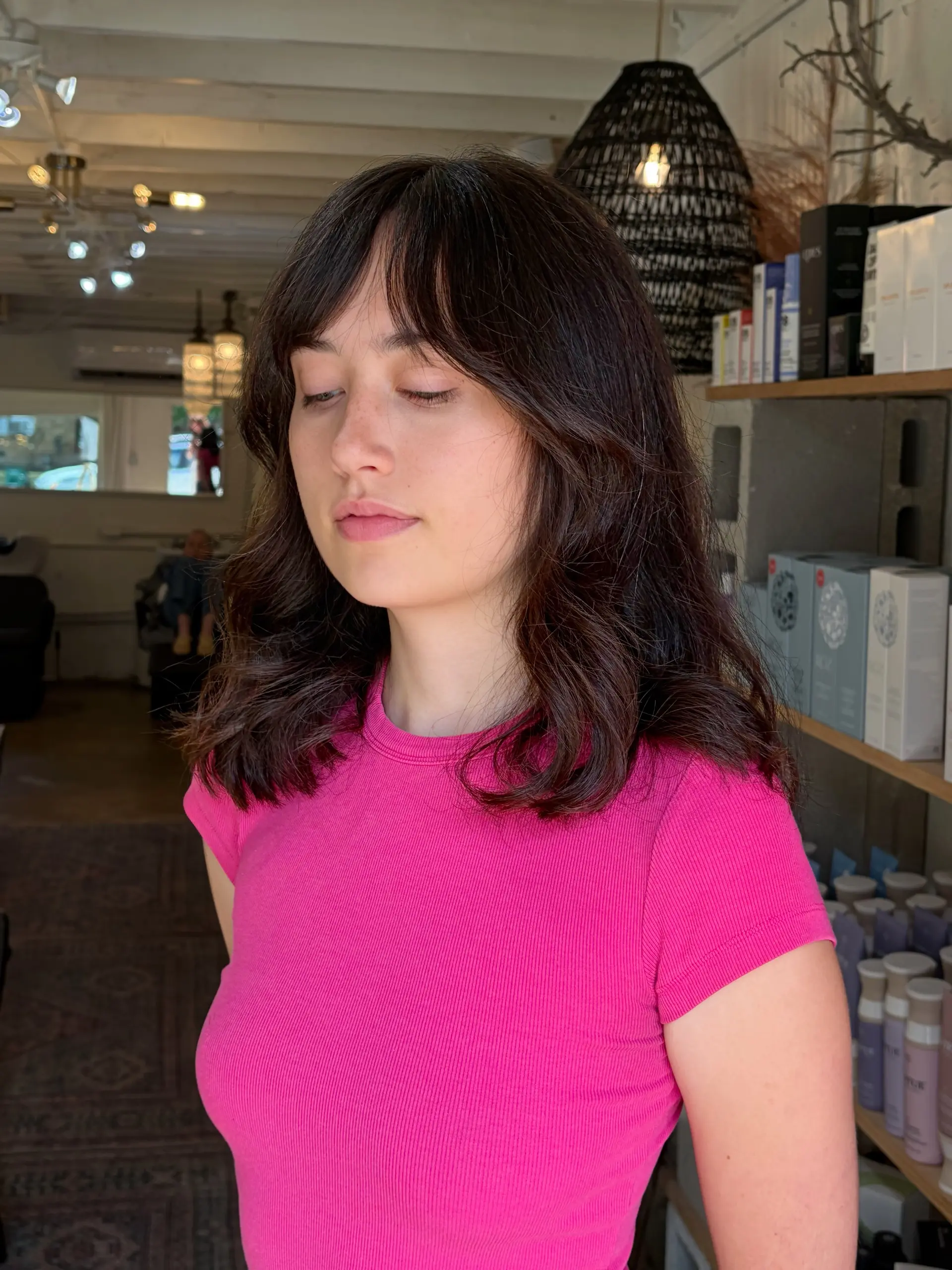 Medium-length dark brown layered hair styled with soft face-framing curtain bangs and gentle waves. 1