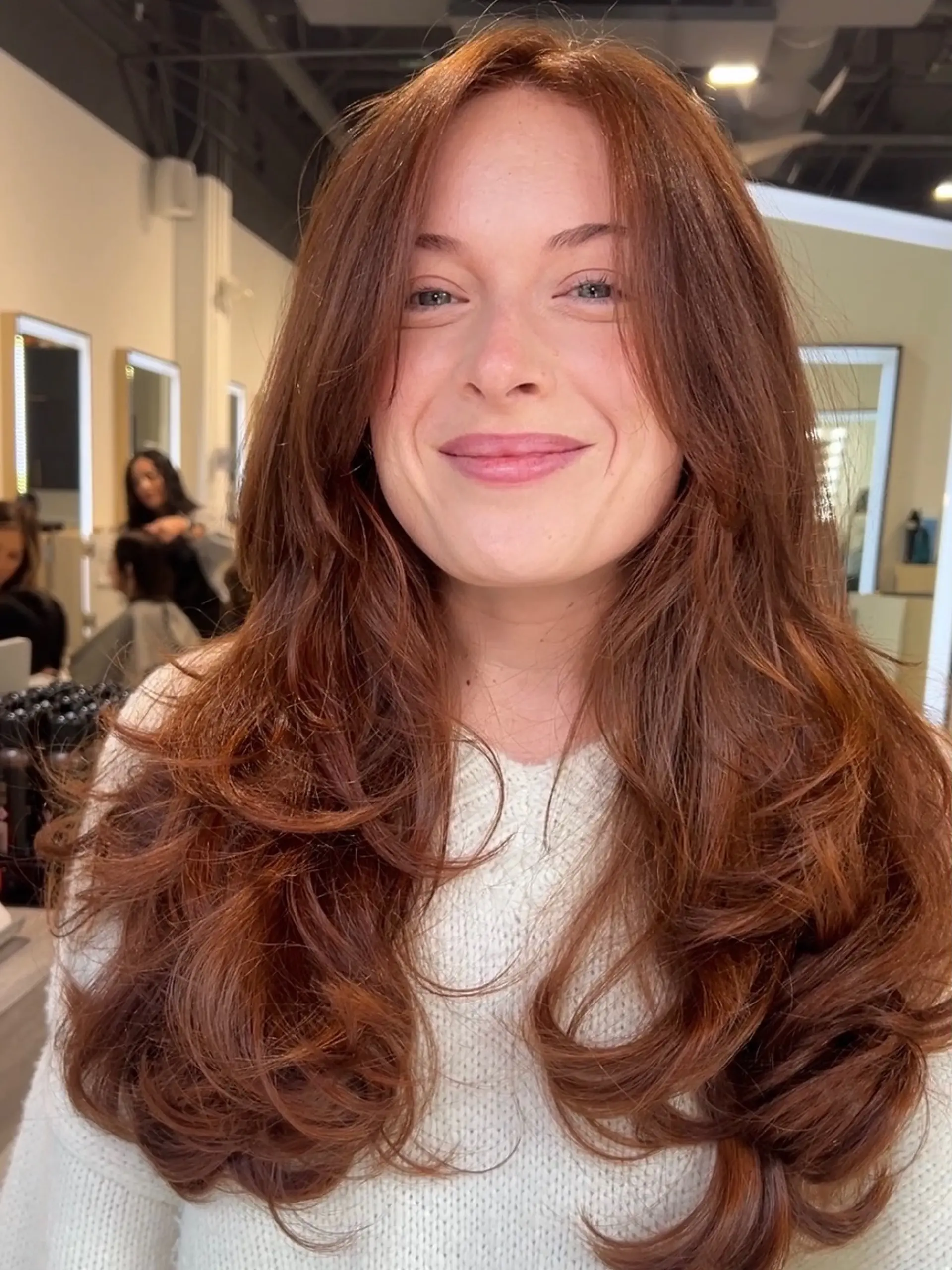 A radiant, all-over warm copper tone styled into voluminous, bouncy layers with softly curled ends. 1