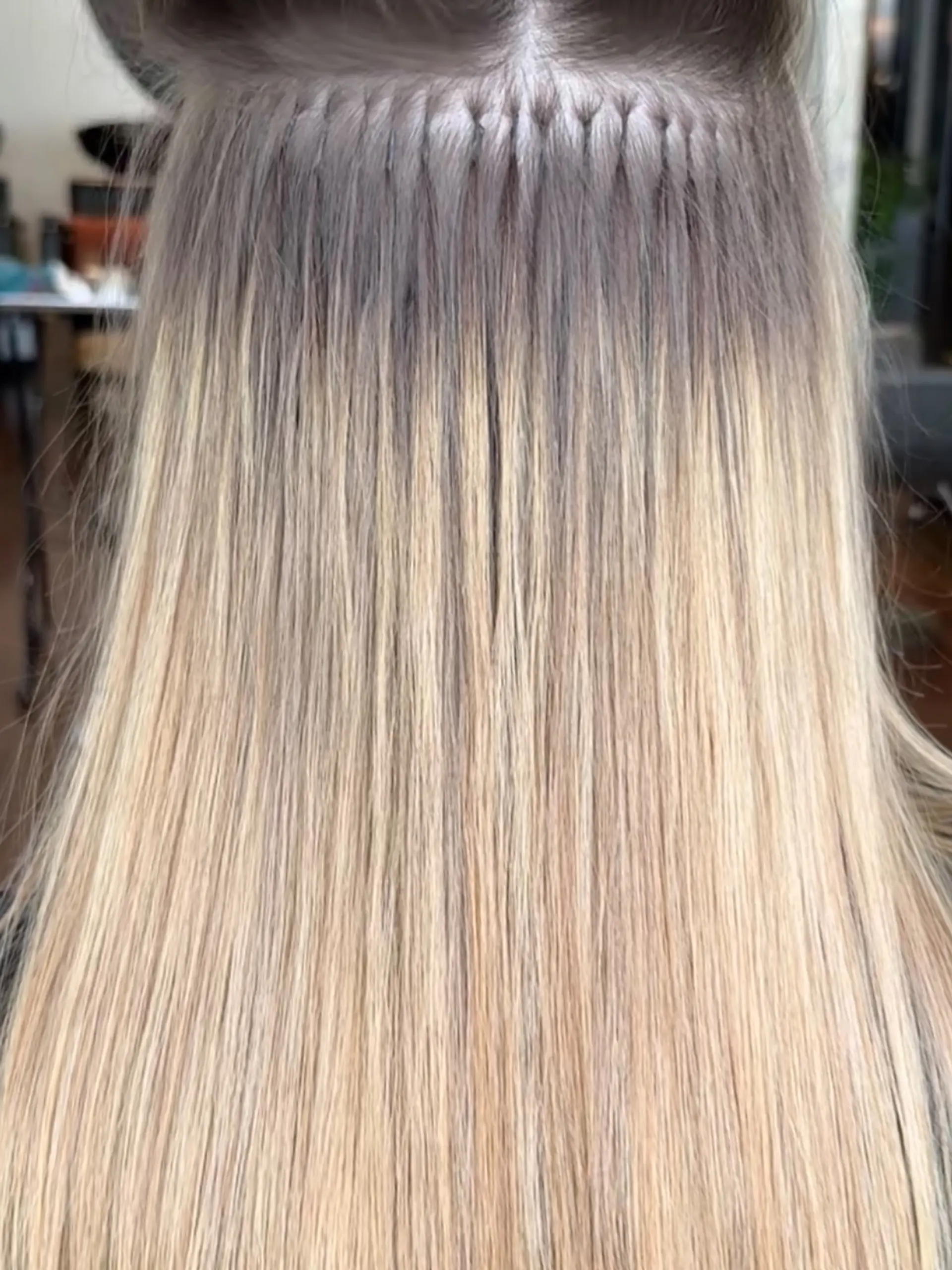 Straight blonde hair showcasing a detailed application of individual keratin-bond extensions. 1