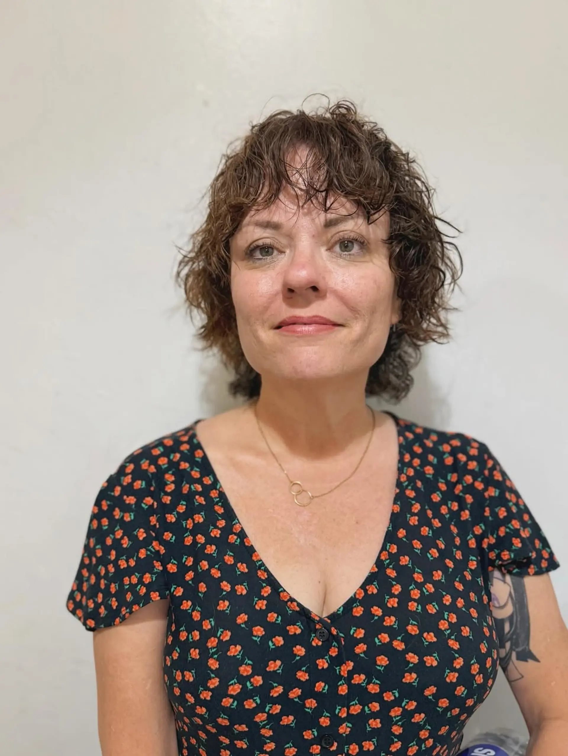 A chic, short curly shag featuring ample texture, layered curls, and playful micro bangs that frame the forehead, giving an effortlessly stylish and voluminous appearance. 1
