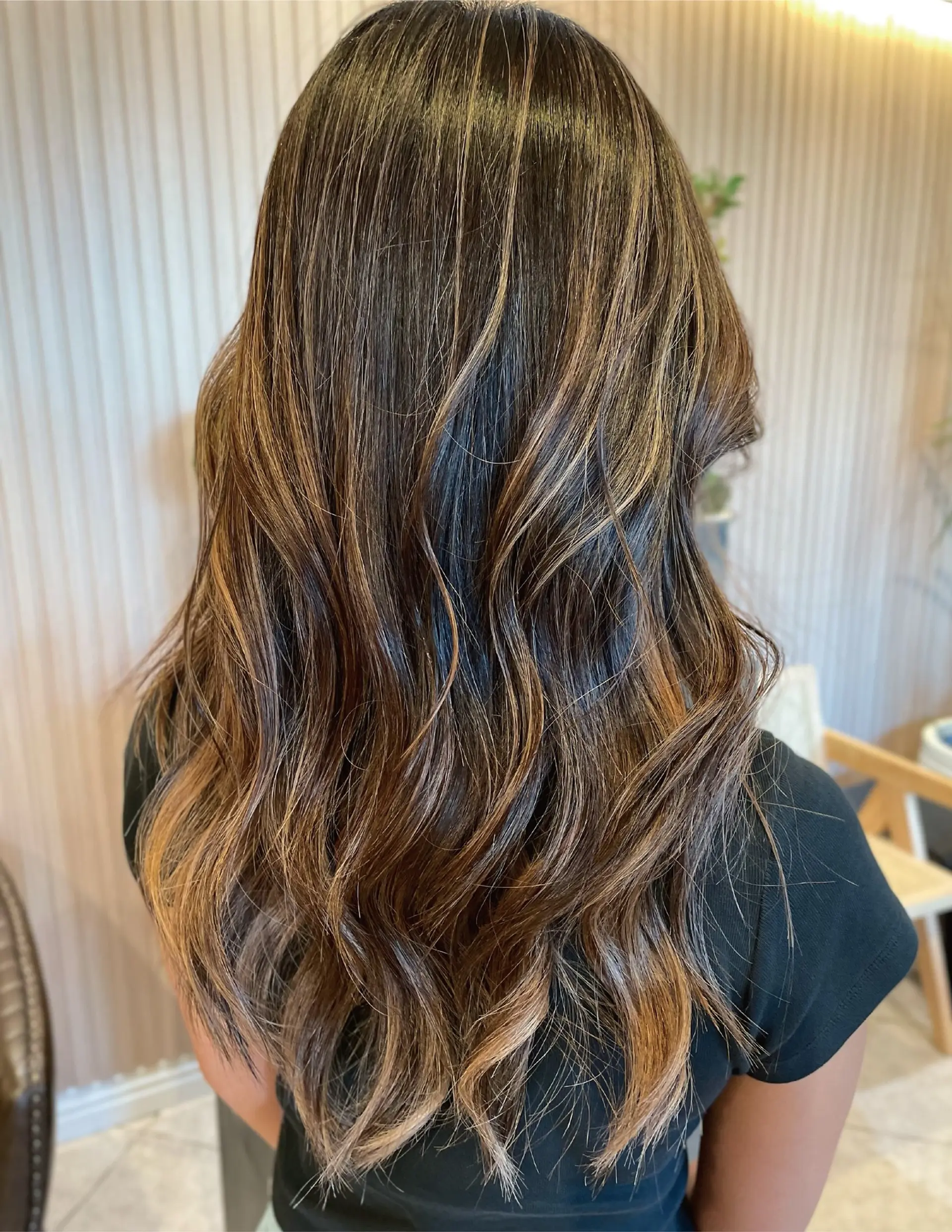 Long dark brown hair styled in loose, soft waves accented by delicate caramel balayage highlights. 1